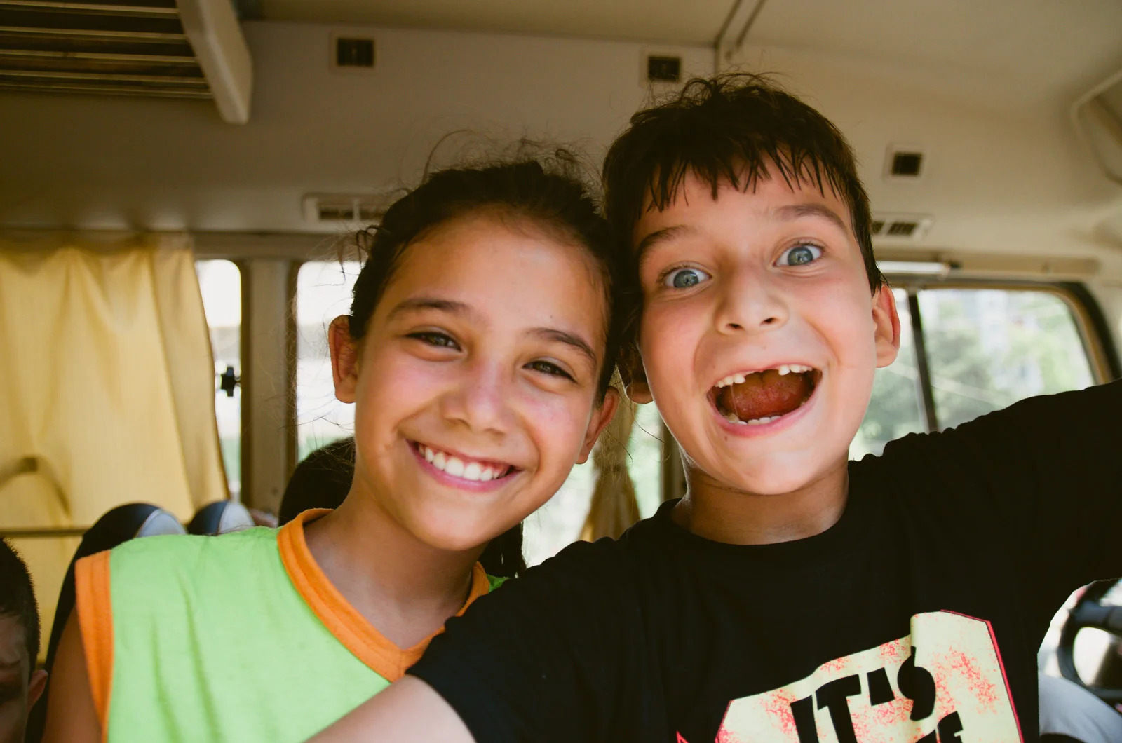 A girl (left) and a boy (right) smile for the camera.
