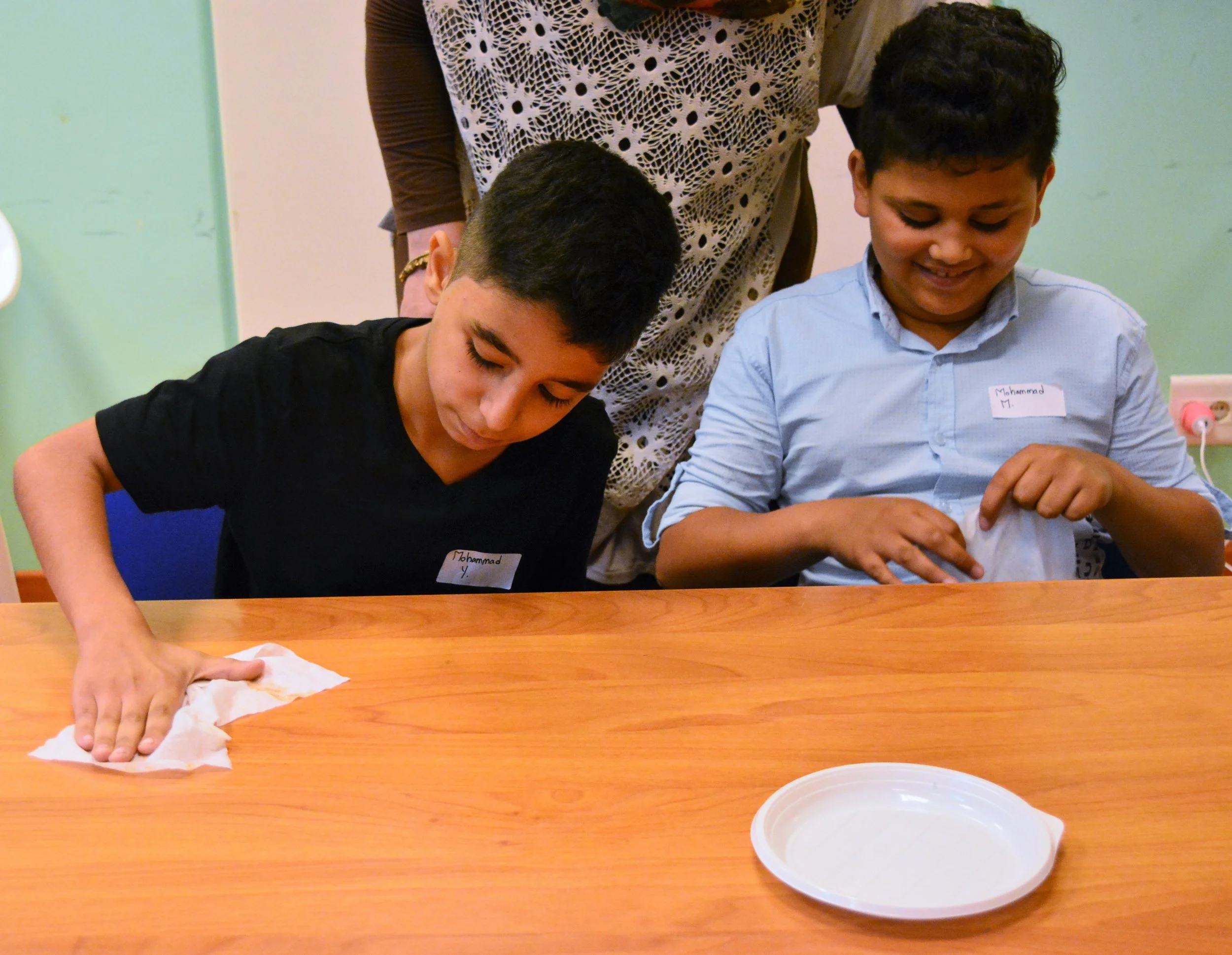 In the picture: two children wipe down a table.