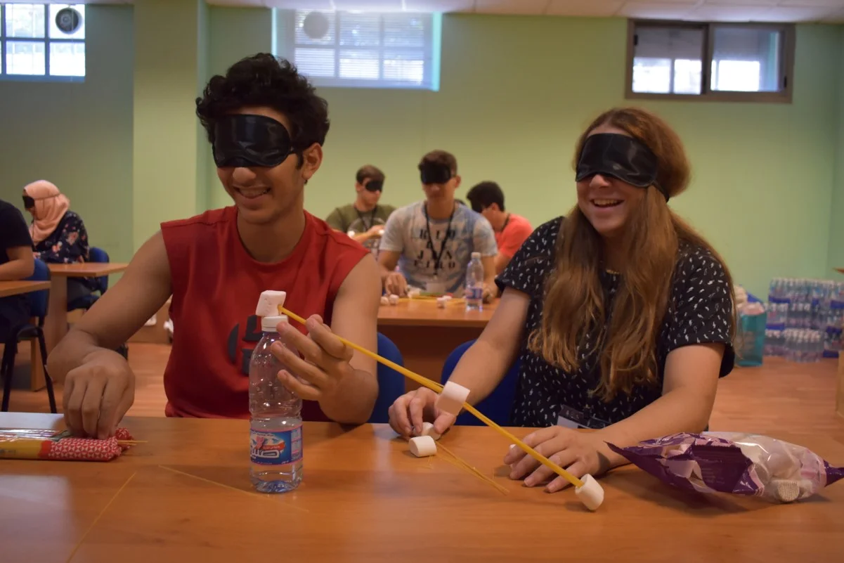 Blindfolded volunteers practicing science experiments (how to build a bridge)