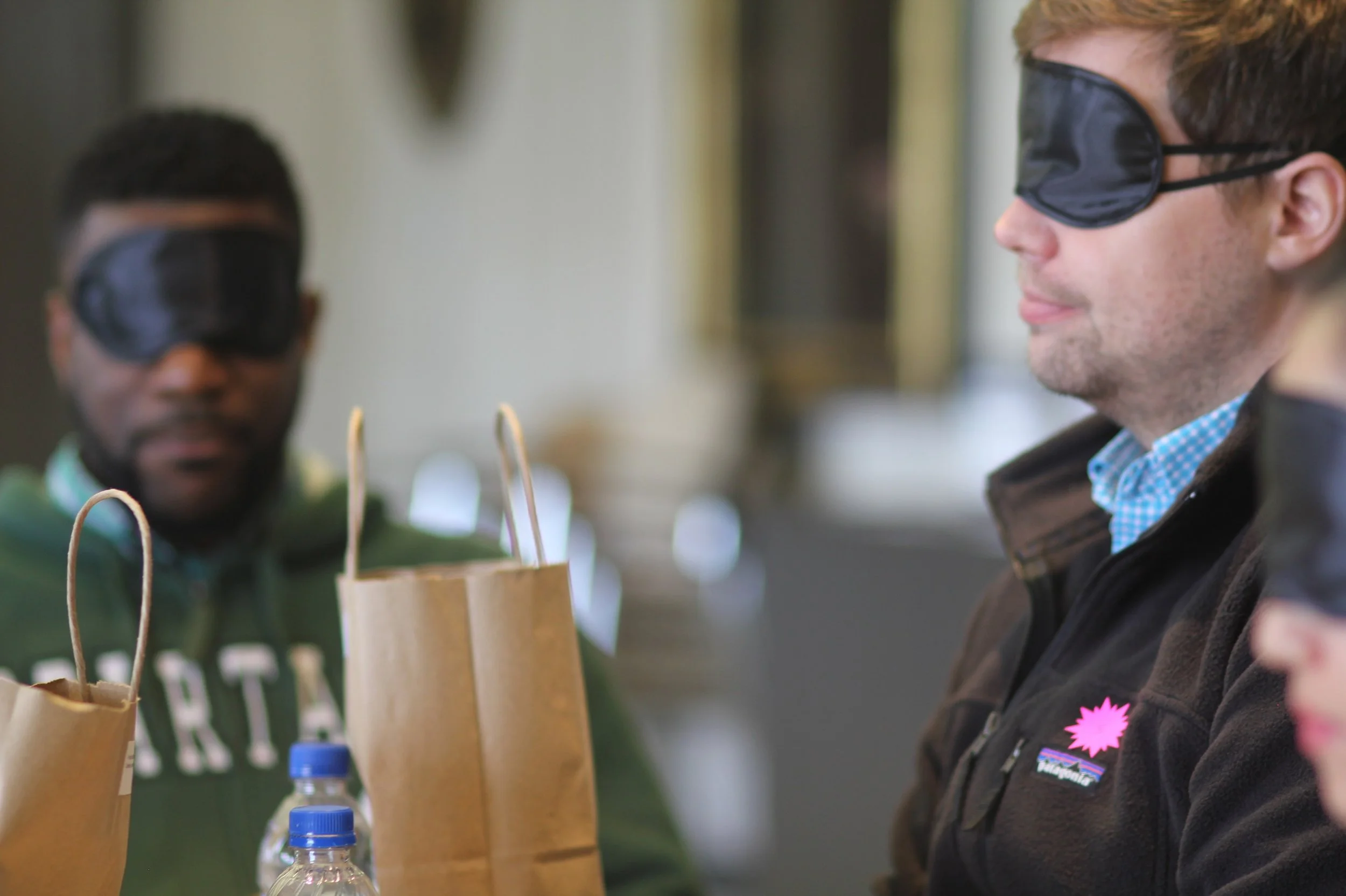 Two blindfolded participants listening intently to the facilitator’s instructions