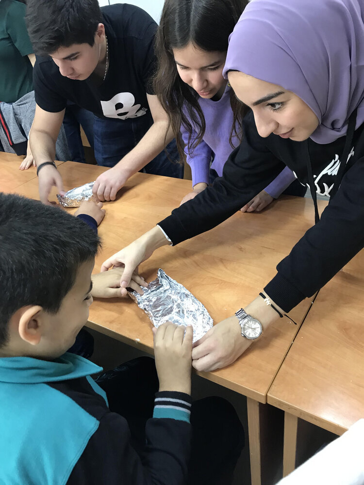 Children talking to a volunteer while doing experiments