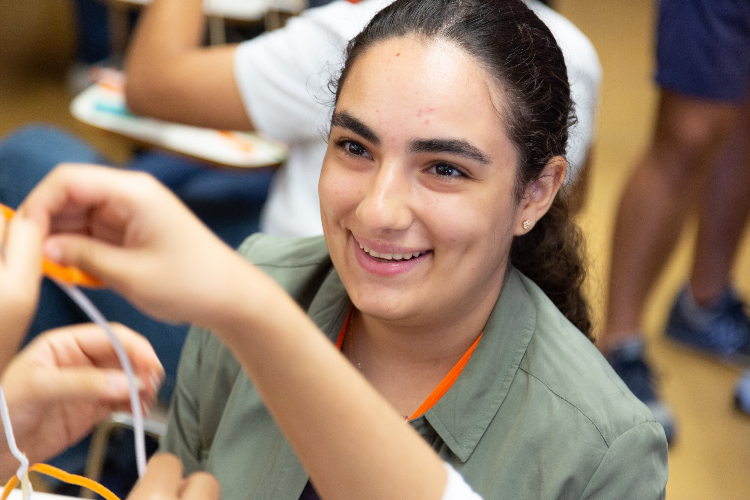 An ETI volunteer smiles as the participants hold up their art project