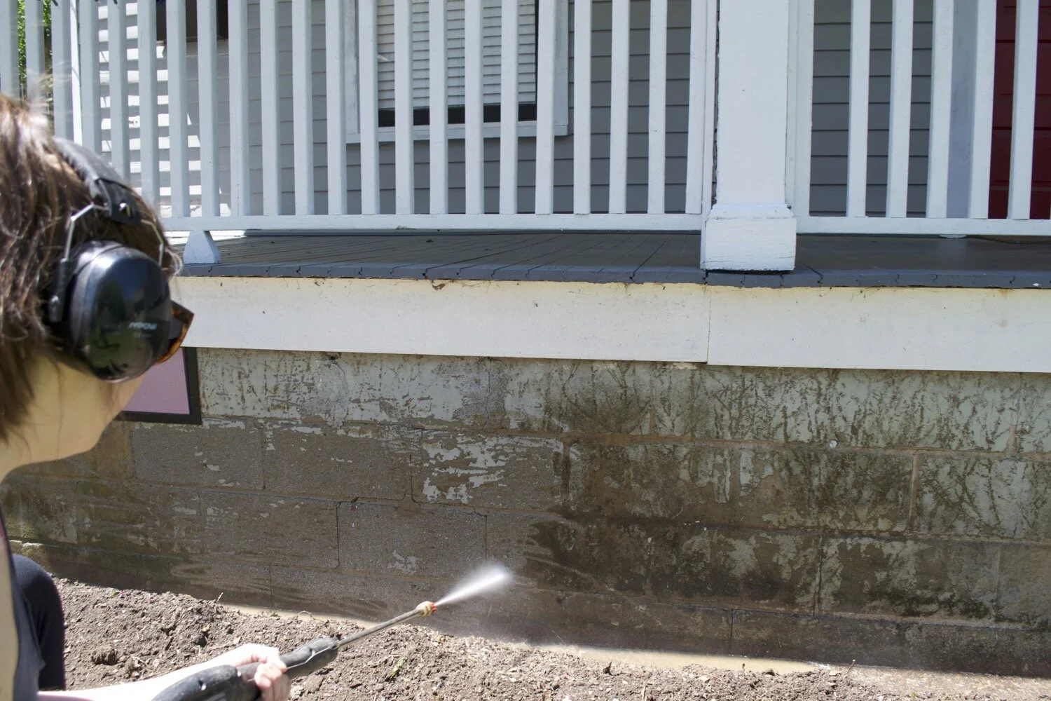 Pressure washing the foundation to prep for painting.