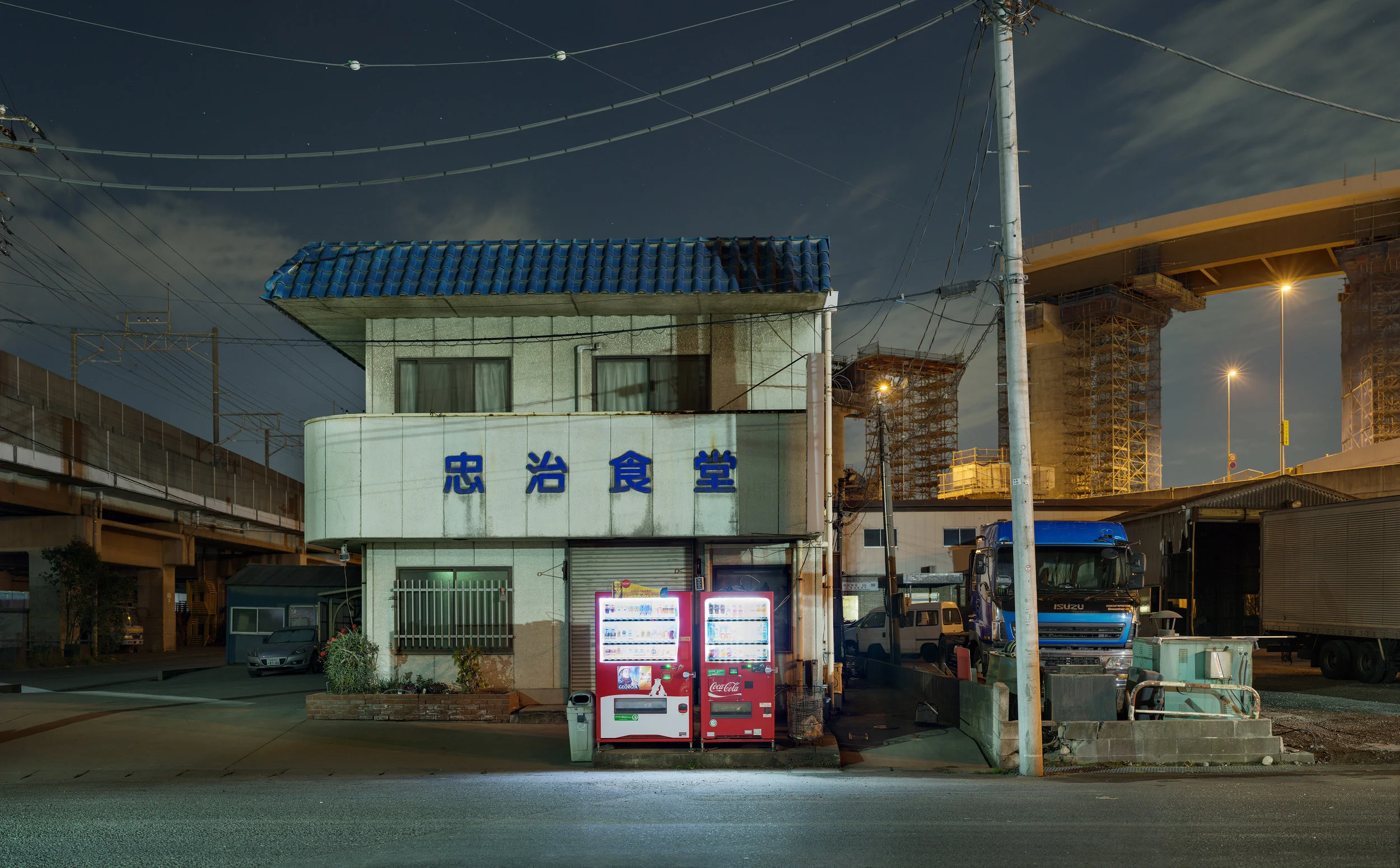 "TOKYO INDUSTRIAL" Series. At first I was drawn to mystery of the night and the enormity of the industry that feeds the largest metropolis in the world. But as I photographed and searched for images in the darkness of the night I have come to realise that what this series represents is the animal that controls and is destroying us. Man's achievements are represented by this stark dystopian world of industry. A world that is amazing for it’s achievements, advancements and power to shape and construct. It is a world that grows and grows signalling our ultimate demise. Whilst shooting this series I have found myself at 4am in the morning surrounded by the buzzing and fumes of chemical plants that run 24/7 starting to dread the world that has been created as I realise that this all signals the planets demise. I fear that mans need to conquer, create and control is unstoppable and that it will irreversibly change this planet into the kind of world that we don't really desire. I revel in the enormity of our construction whilst feeling the horror of what it means. Buy Prints from this series.