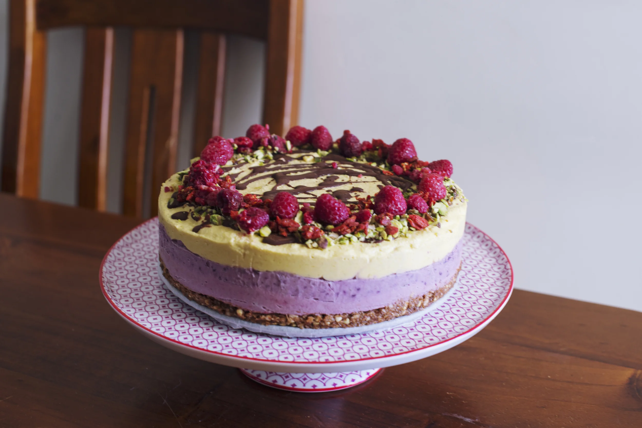  raw vegan mango blueberry raspberry cheezecake topped with organic cacao choc, pistachios, goji berries and more raspberries
