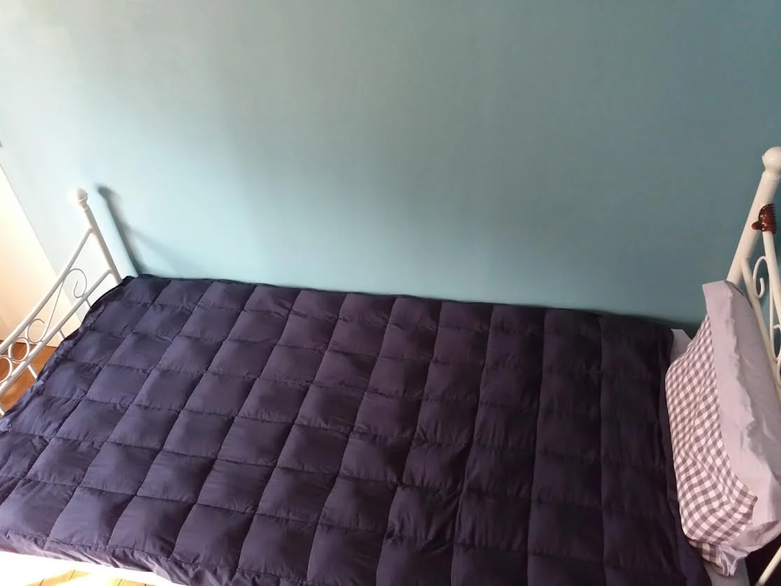 A dark blue weighted blanket shown full size on a bed.
