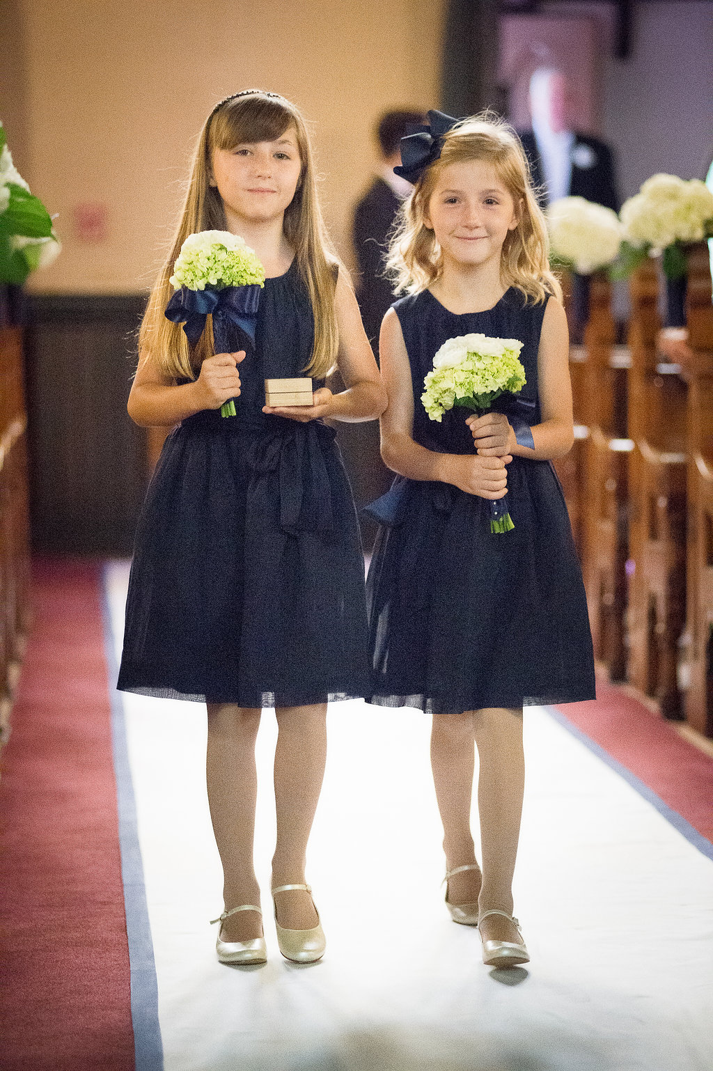Here are the "ring bearer girls" with small bouquets of white hydrangea and ranunculous tied with an exaggerated bow for a youthful look to the bouquets.