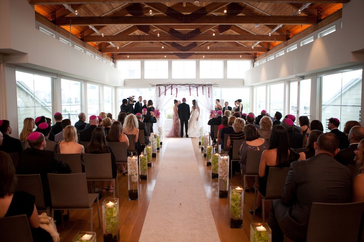 The ceremony was held on the top floor of the venue, a very large room with exposed beams, white walls and lots of windows. We created a structured Chuppa and draped it with sheer white fabric to allow the light from the windows in. The decor was a simple branch design to pull in a natural look with hanging purple dendrobian orchids to add a pop of color to the piece.