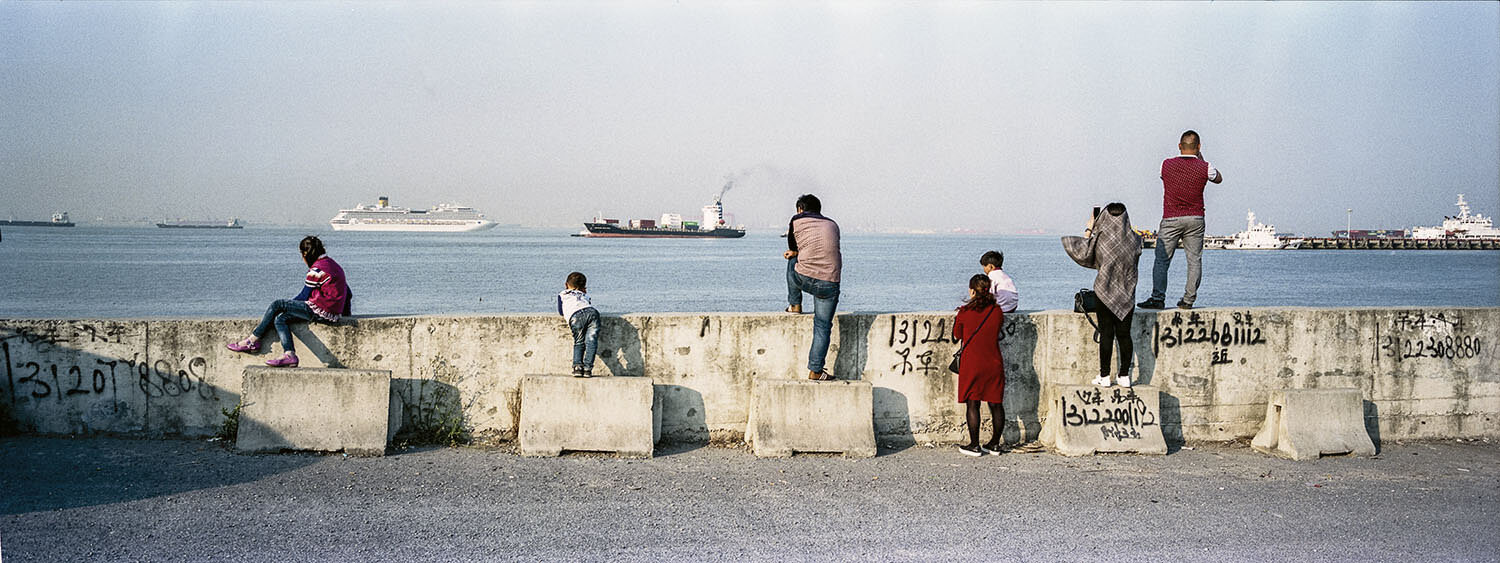  April 23, 2017, Shanghai, China - Sightseers watch ships go by near a commercial dock near the mouth of the Yangtze River.  