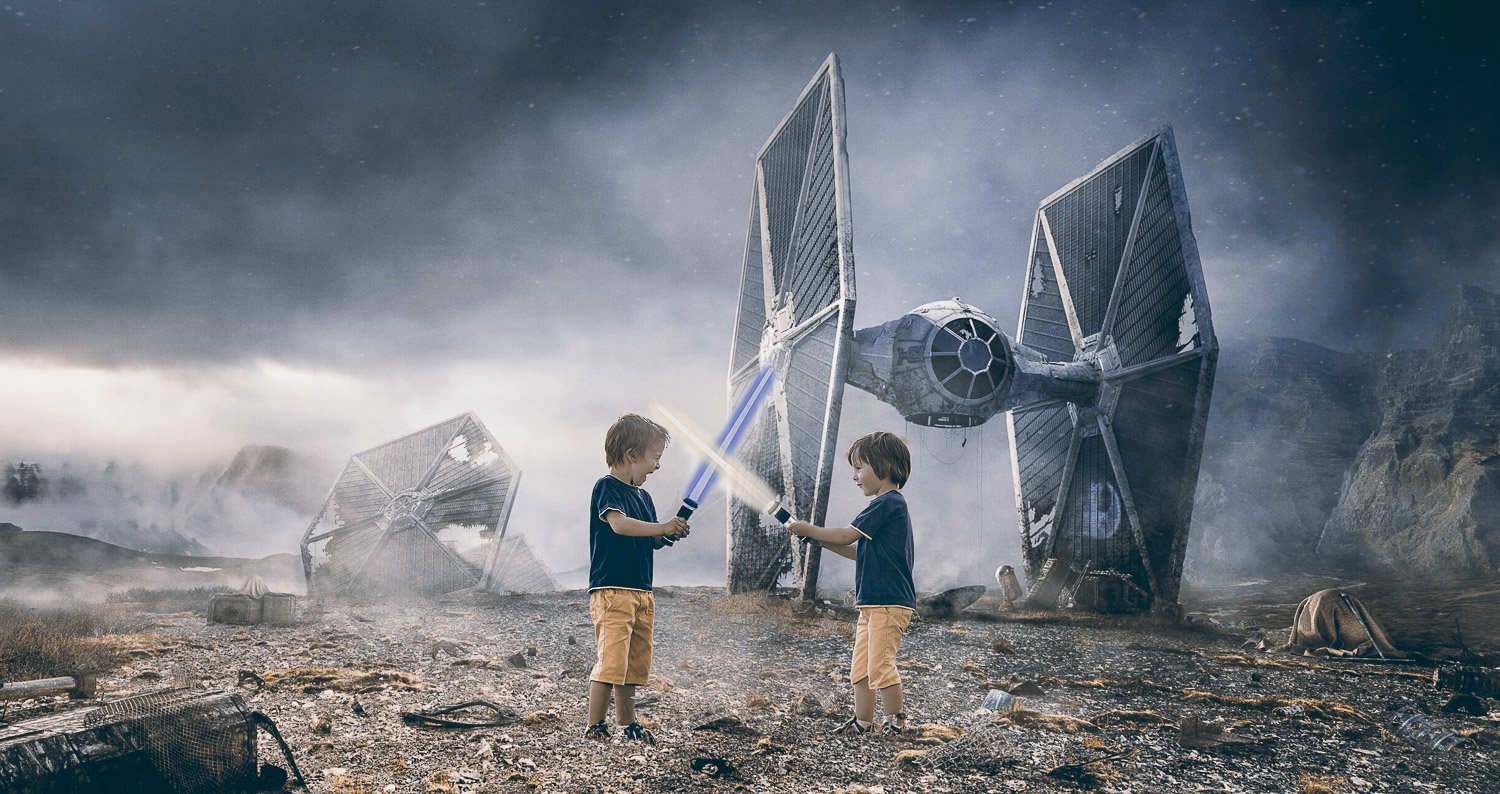 Two boys playing with lightsabers in a Star Wars themed background