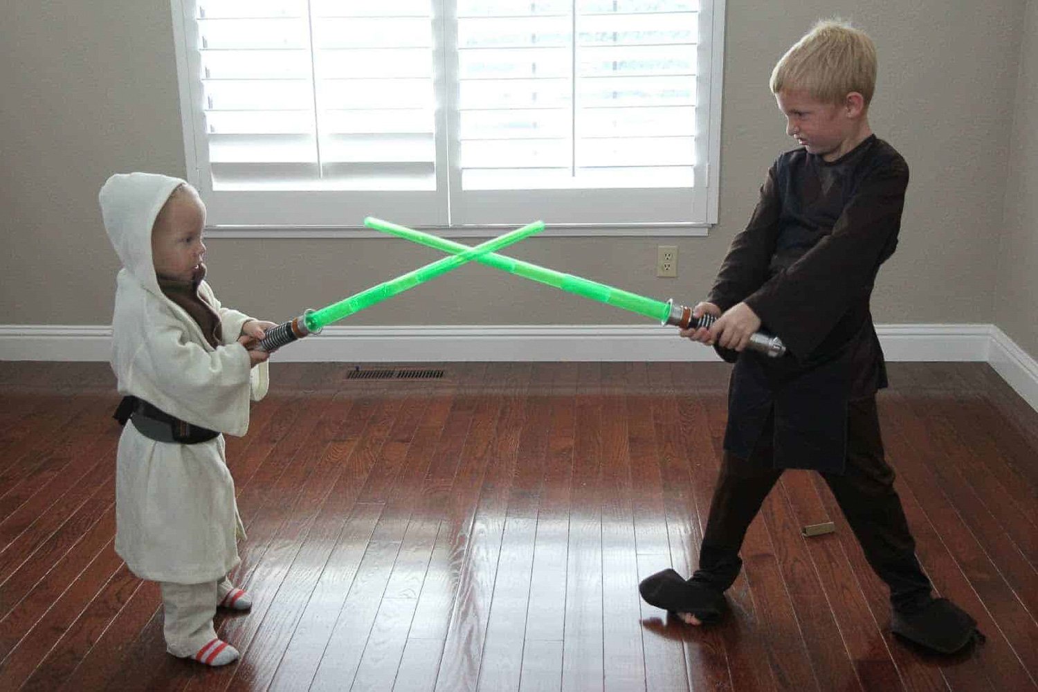 Two boys playing inside with toy lightsabers