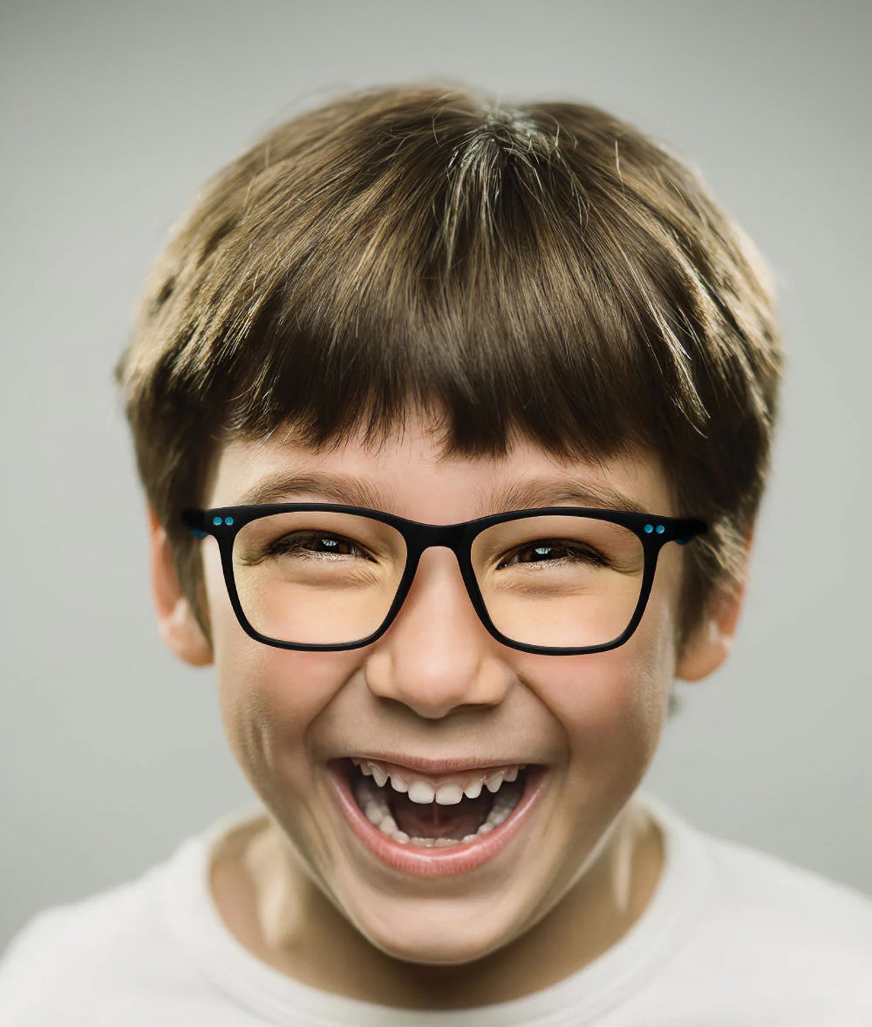 A close up of a boy wearing glasses smiling at camera