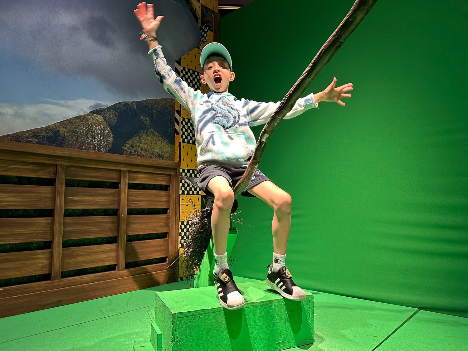 A young boy riding a broomstick in a studio