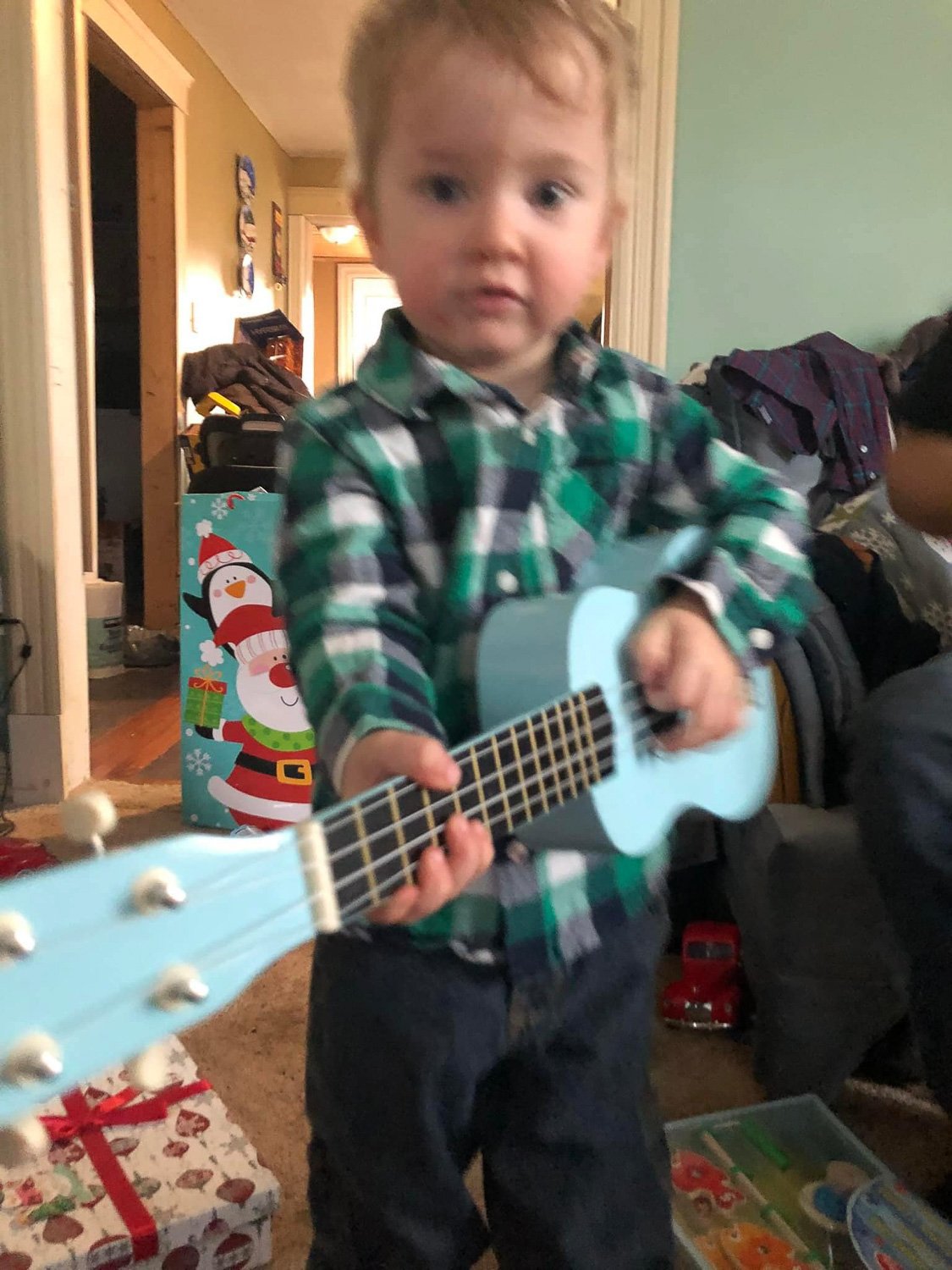 A little boy standing and holding a ukulele