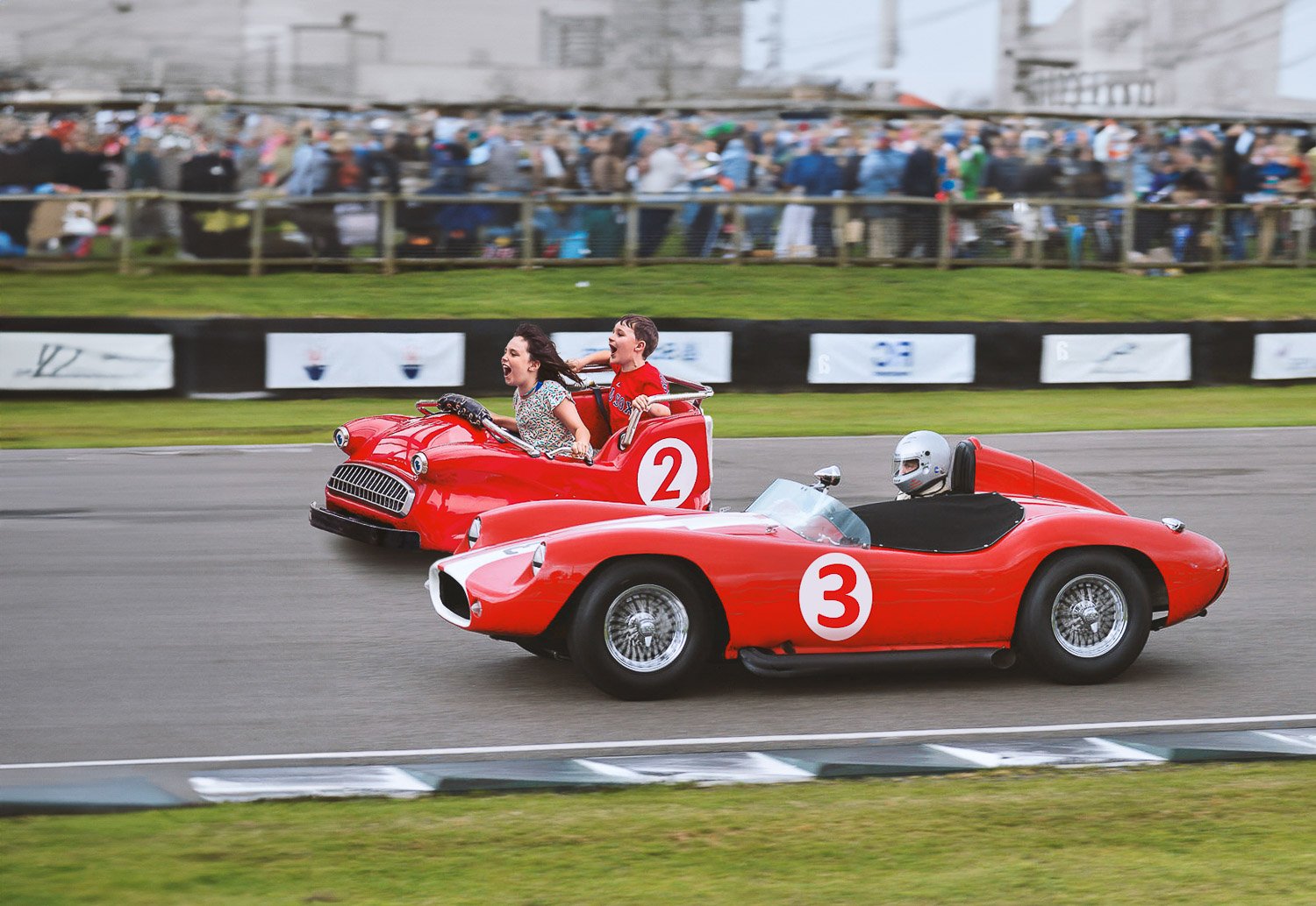 A boy and girl in a red racing car on race track