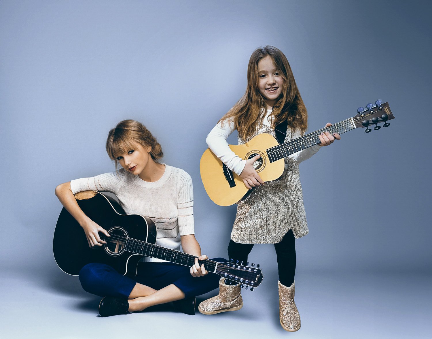 A young girl holding a guitar standing next to Taylor Swift