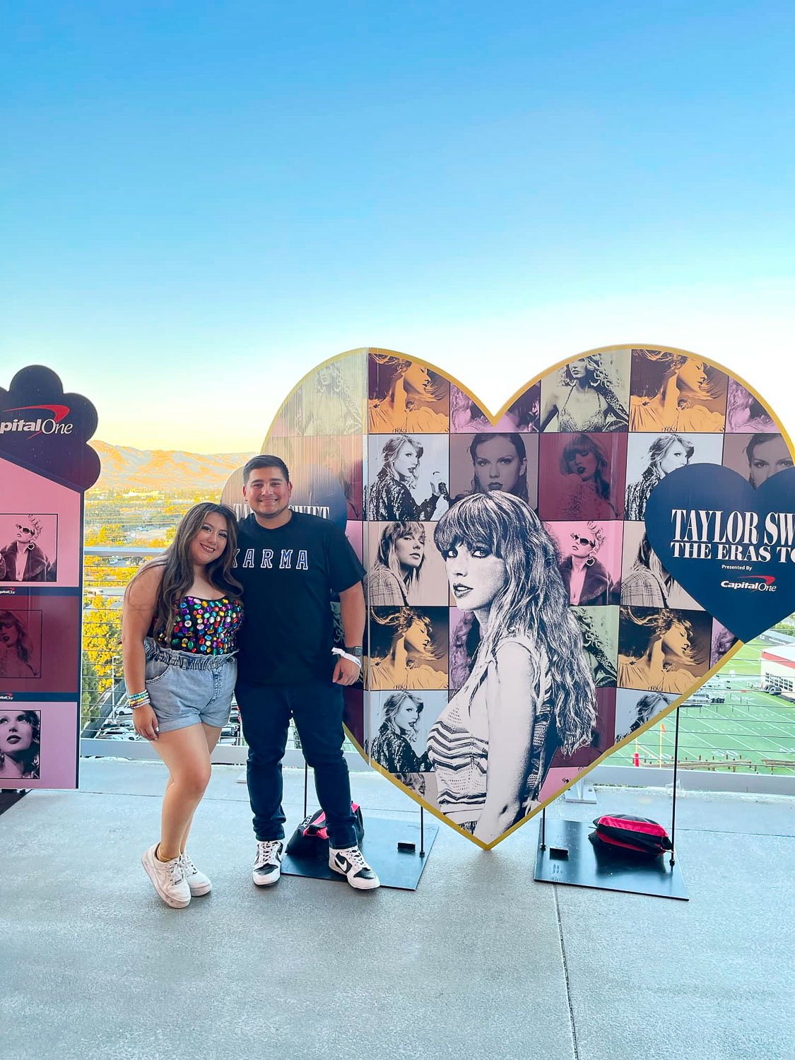 A young couple standing in front of heart shaped billboard