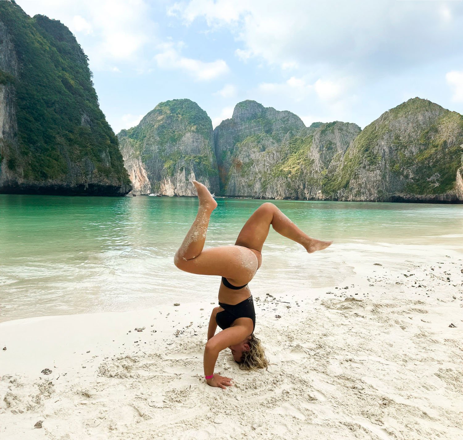 A woman doing a headstand on a beach