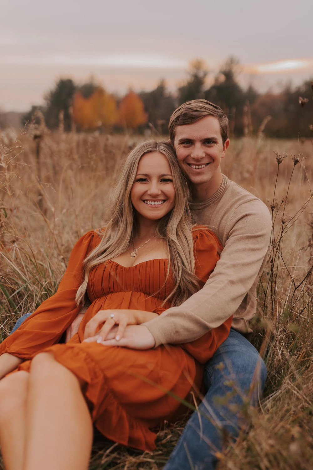 A couple sitting in a grassy field smiling