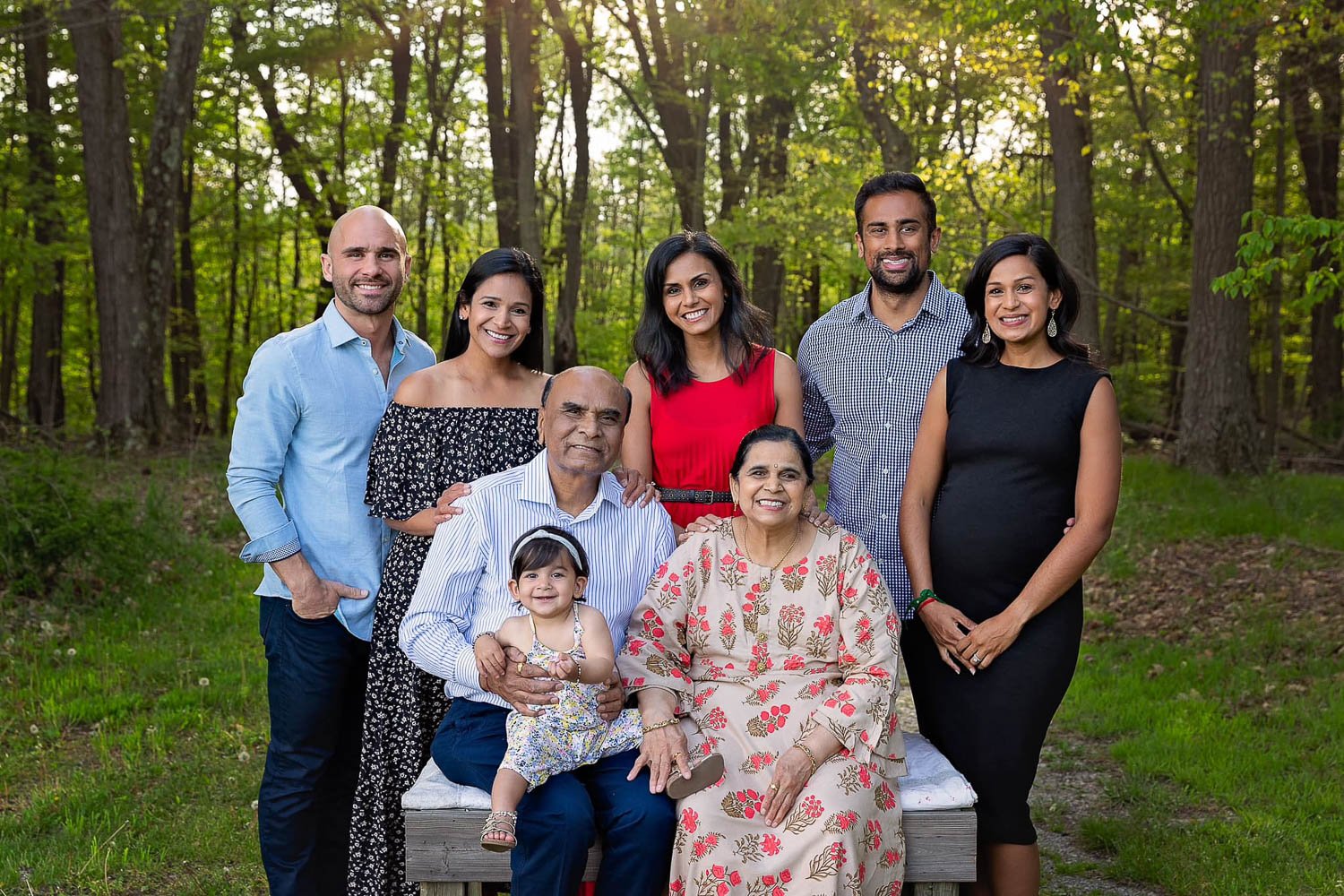 A family of eight posing for group shot outside in leafy setting in a 