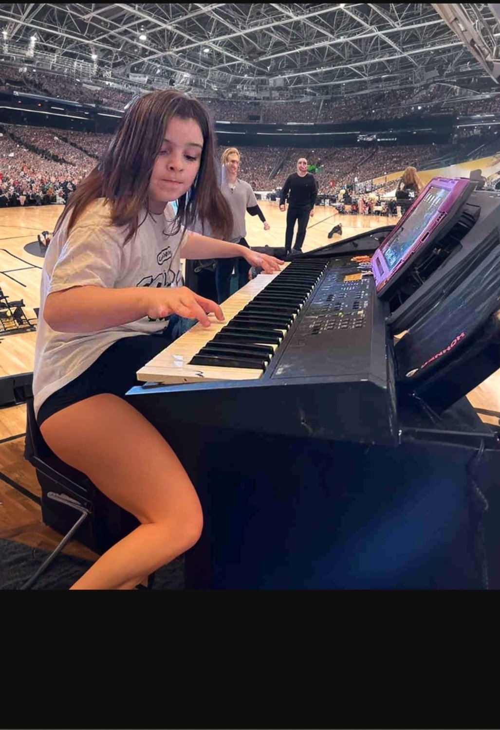 A young girl playing keyboard in sporting arena