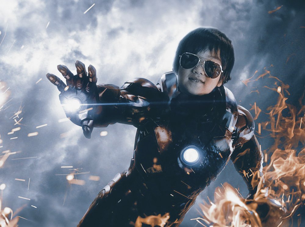 Young boy in Iron Man costume flying in a fiery sky 
