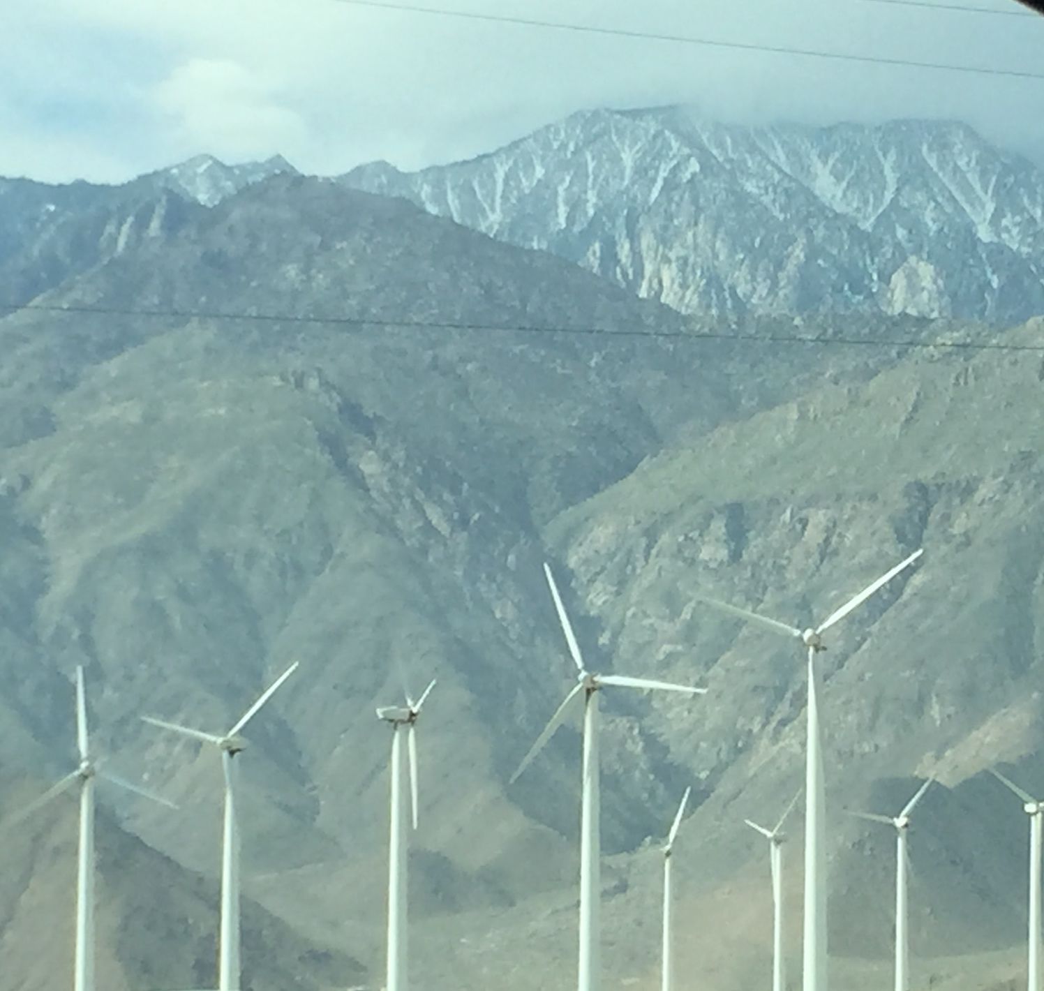 Windmills in the Palms Springs area with the San Jacinto Mountains peaking out with sparse snow.