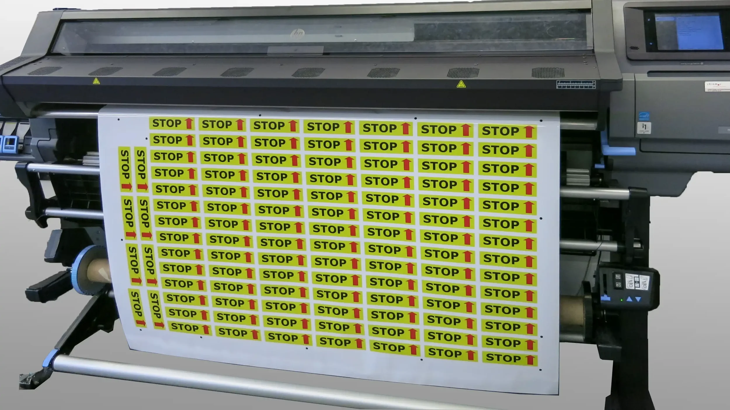Grossformat-Drucker mit mehreren gelben 'STOP' Aufklebern auf Selbstklebefolie.