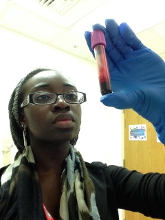 ILS student holding up a vial of blood in a biological lab.