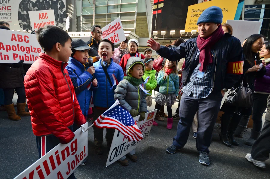 Activist directs children to yell “killing is not a joke” to protest Jimmy Kimmel for airing a segment of the Kids Table show, in which a 6-year-old boy responded “kill all the Chinese” as the solution to U.S. debt owed to China. The children, too young to understand the context of the protest, still have smile on their faces.