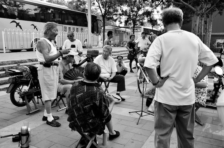 Retirees gather on the streets of Beijing to practice “Peking Opera.”