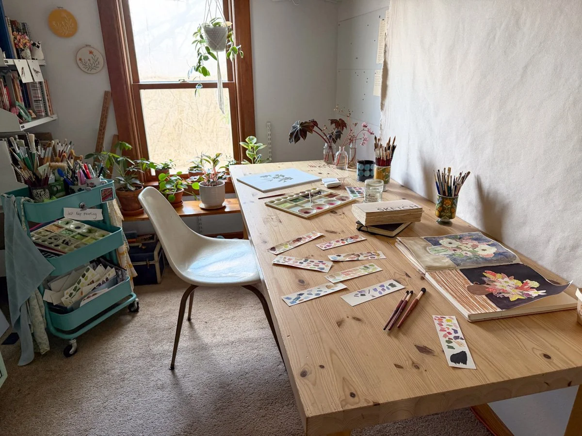 sketchbooks, swatches and a watercolor painting in process on the art table in my studio