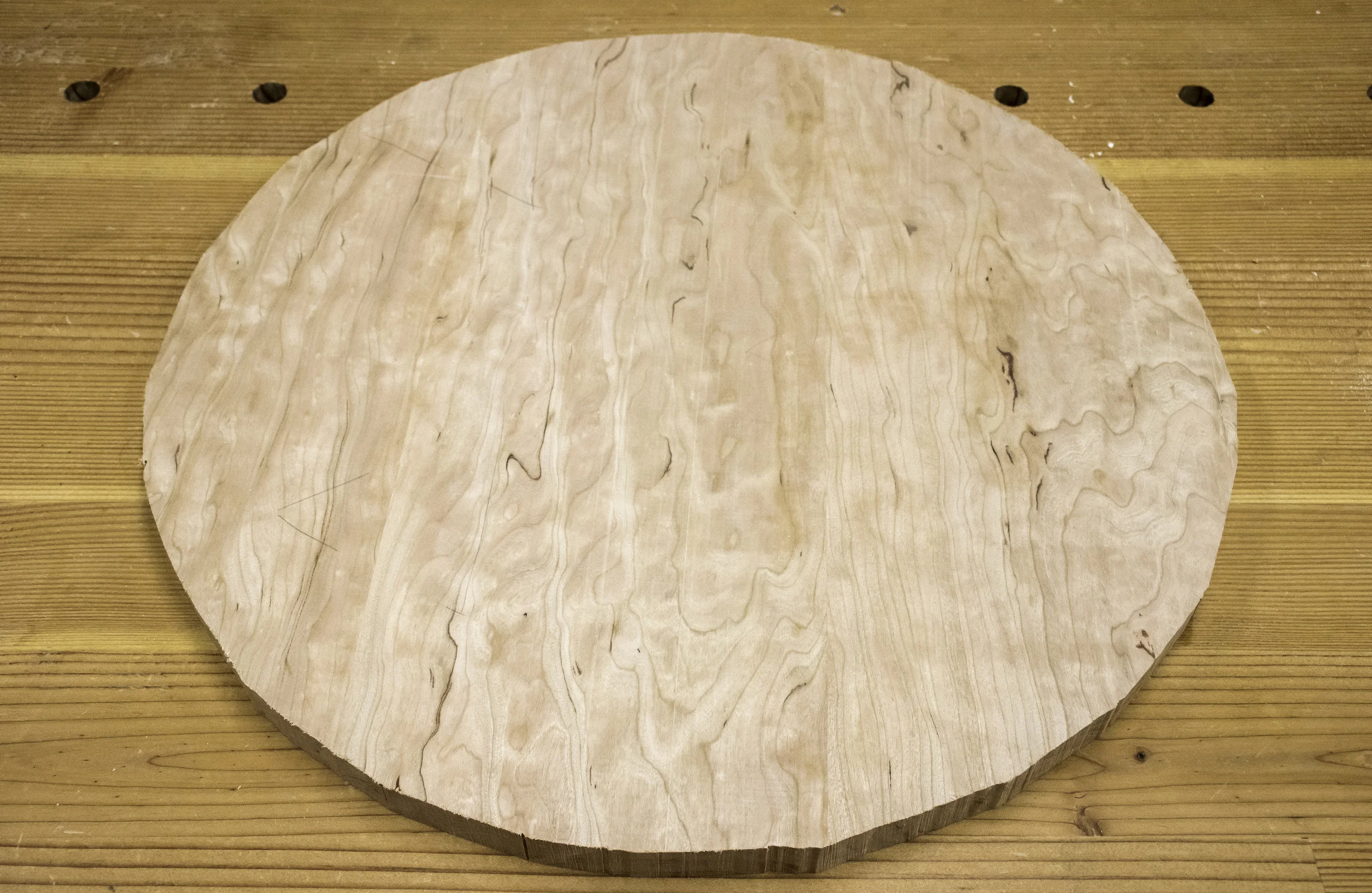 A circle-ish object emerges from the bandsaw.
