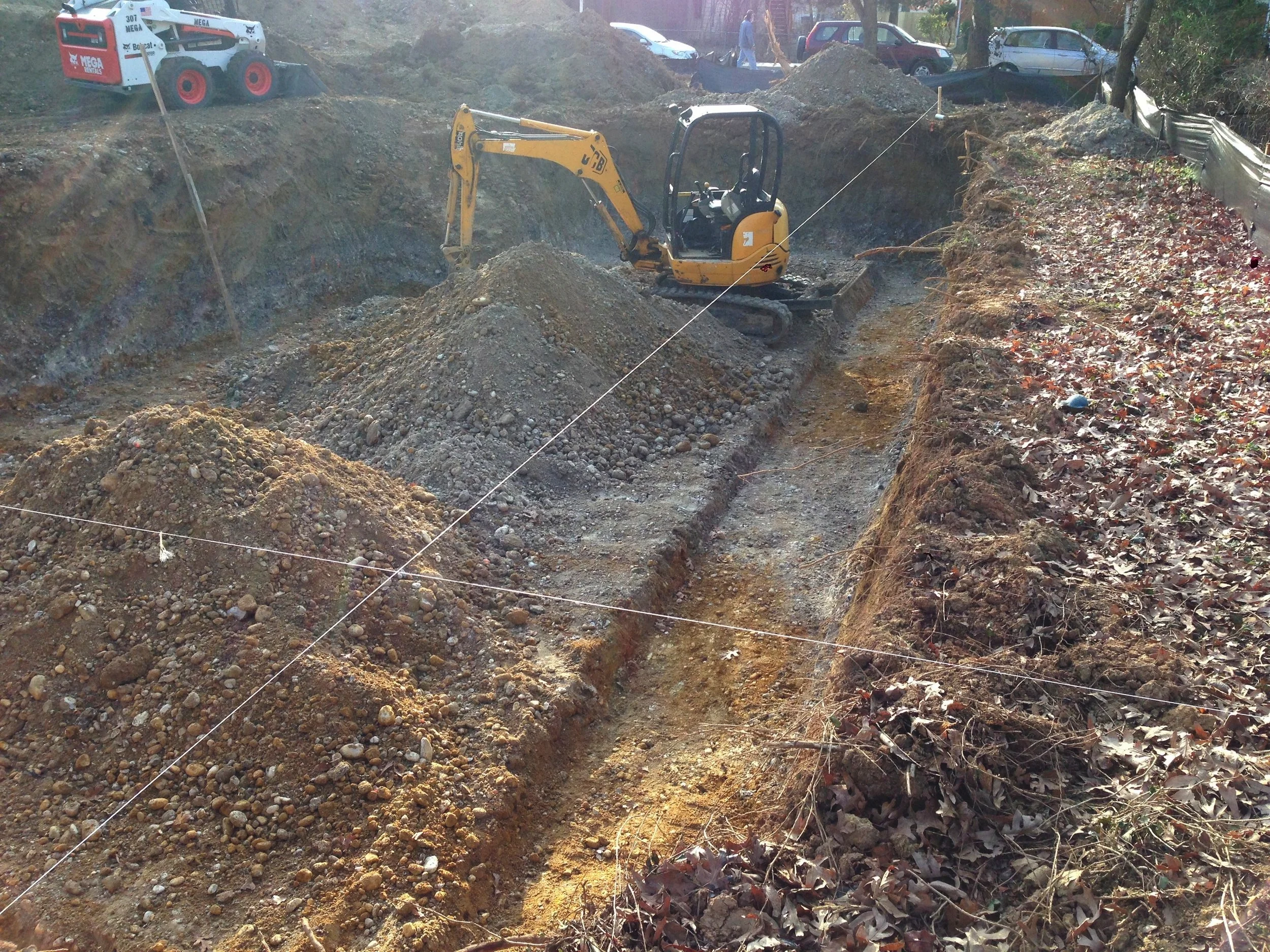 Excavation for the footings tanking place. The strings represent the walls and they are aligned at the ground with a plumb bob . I love this tool. So simple yet so useful.