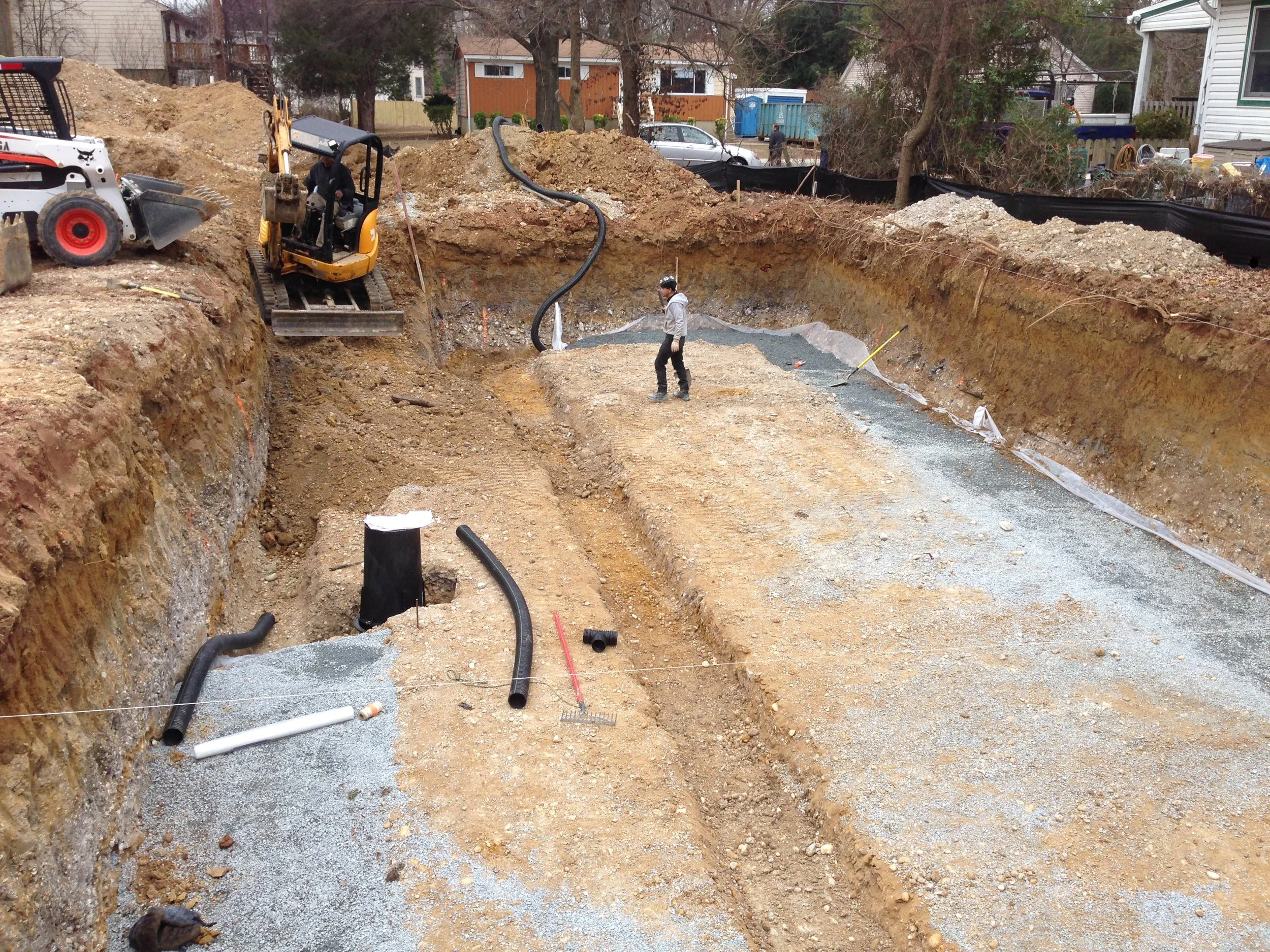 Perforated pipe snaking its way around the footing towards the sump pump basin. Also the footing for the interior load bearing wall has been excavated. 