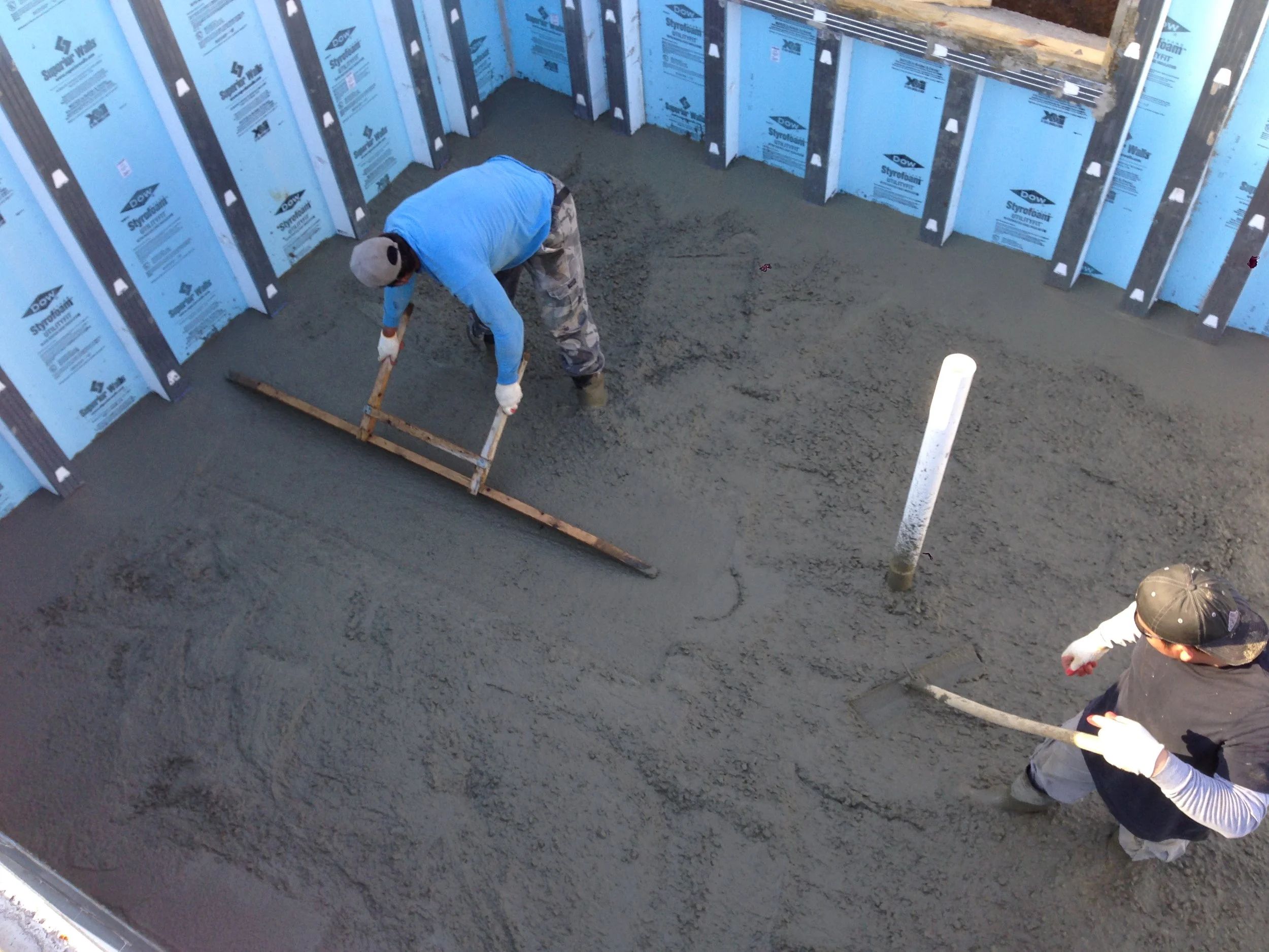 Jose leveling the slab. Each stud along the wall is marked with a chalk line and every 5' in each direction they place rebar at the correct slab height.