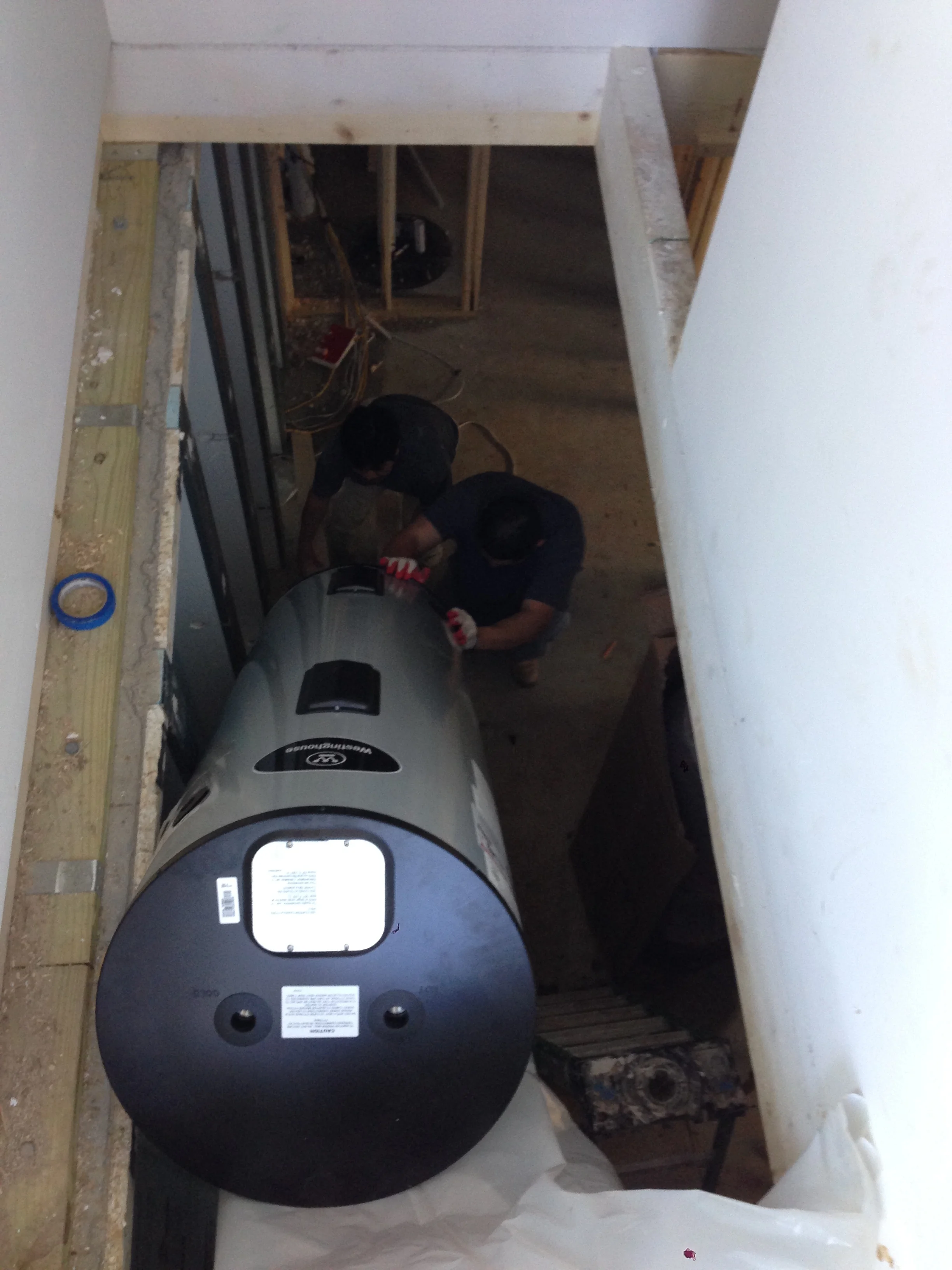 Moving the electric heater to the basement on a ladder. I can't wait for the stairs to be installed.