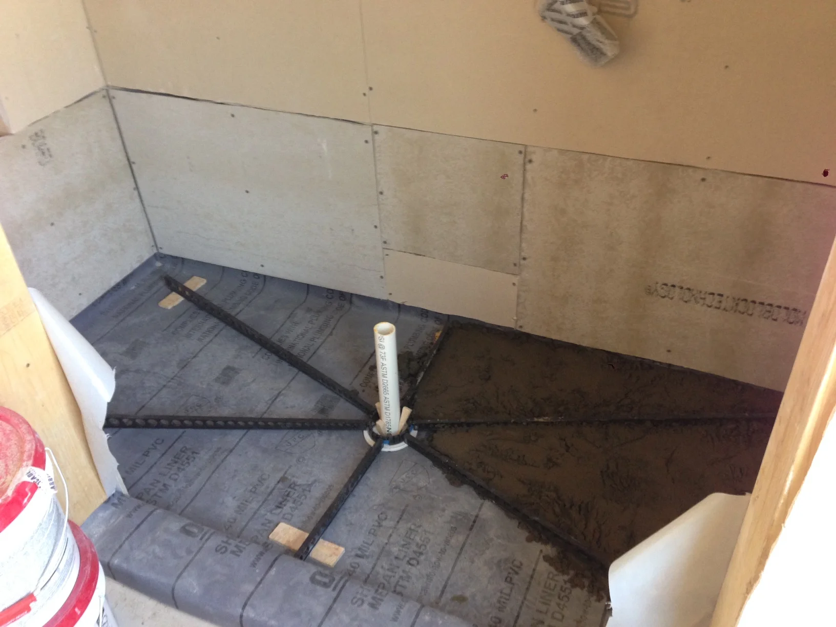 Since I am not a professional I bought some guides that give the proper slope for drainage. The gray part on the base is called a pan liner which is pretty thick and heavy. Below that we installed plastic along the walls up 30". This is to help with the humidity that will build up during those long stem showers. Can't wait!