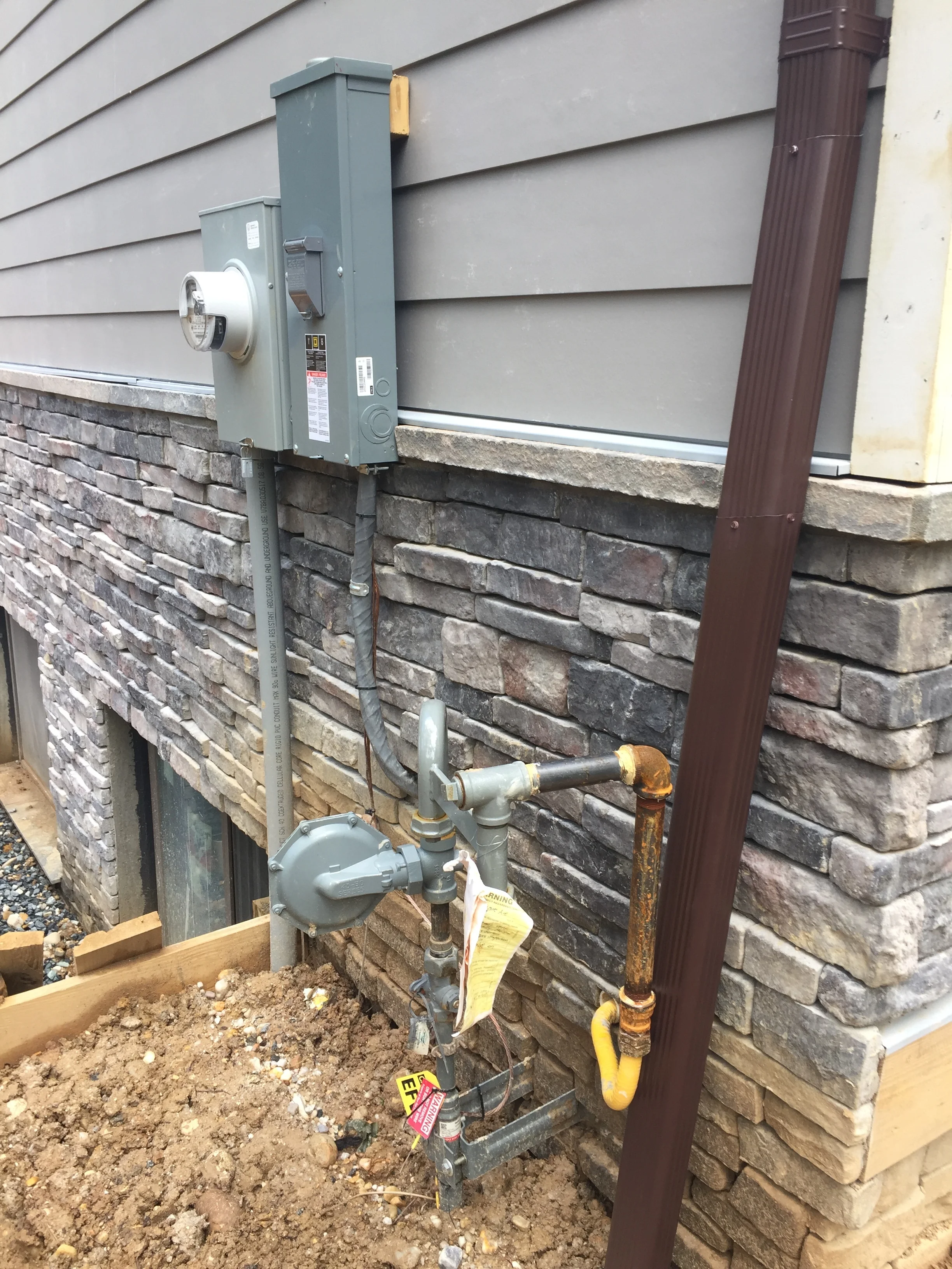 Isn't this a thing of beauty? My gas line, my electric line, my downspout and a hose bibb hidden somewhere behind everything is all installed. 