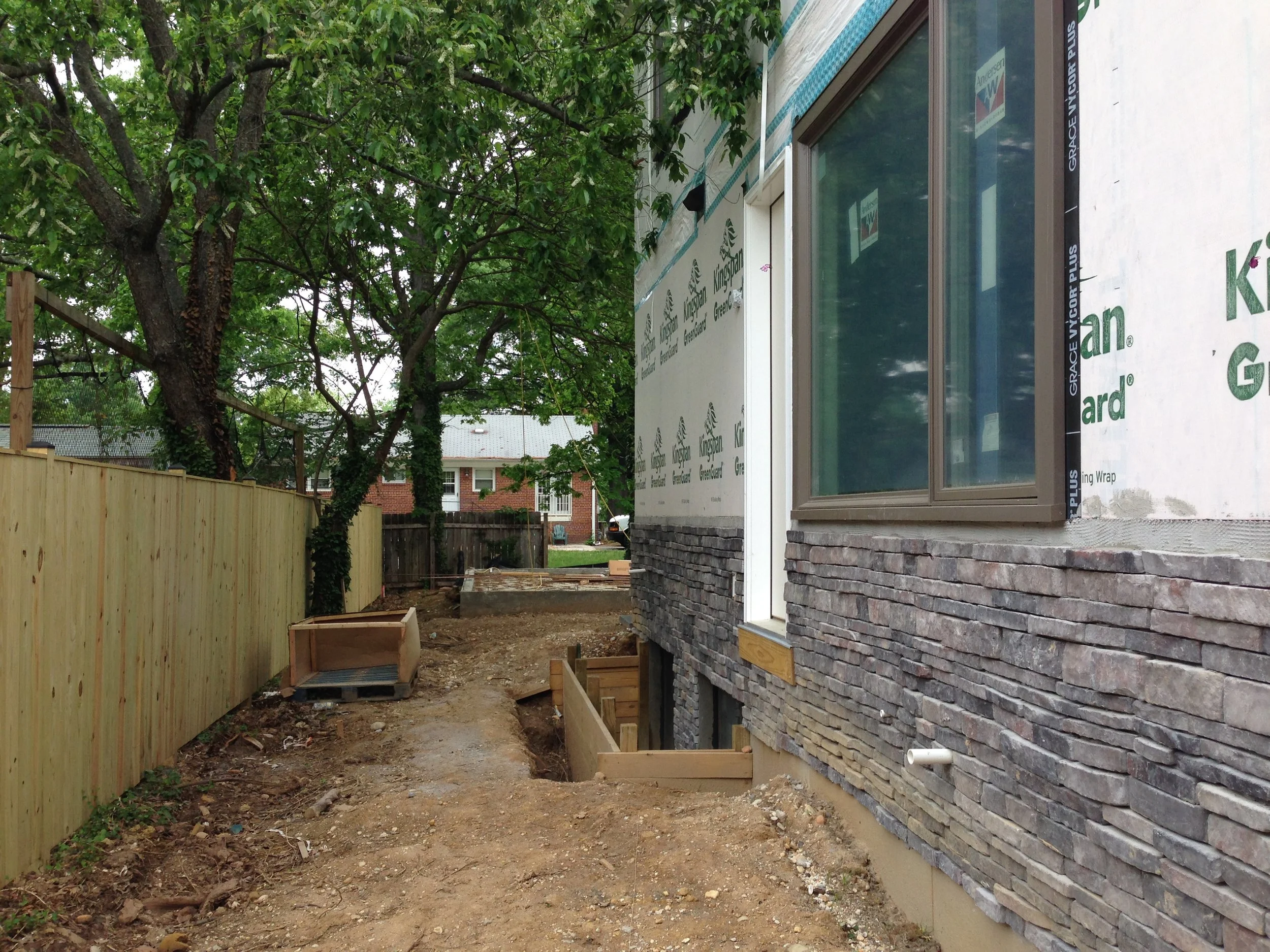 This is an old photo before the siding was installed. All the way at the back of the wall near the corner there is a white PVC pipe coming out. There should have been another PVC pipe above that one in the siding area. This photo proves that the condensing pipe was never installed at the exiting area. 