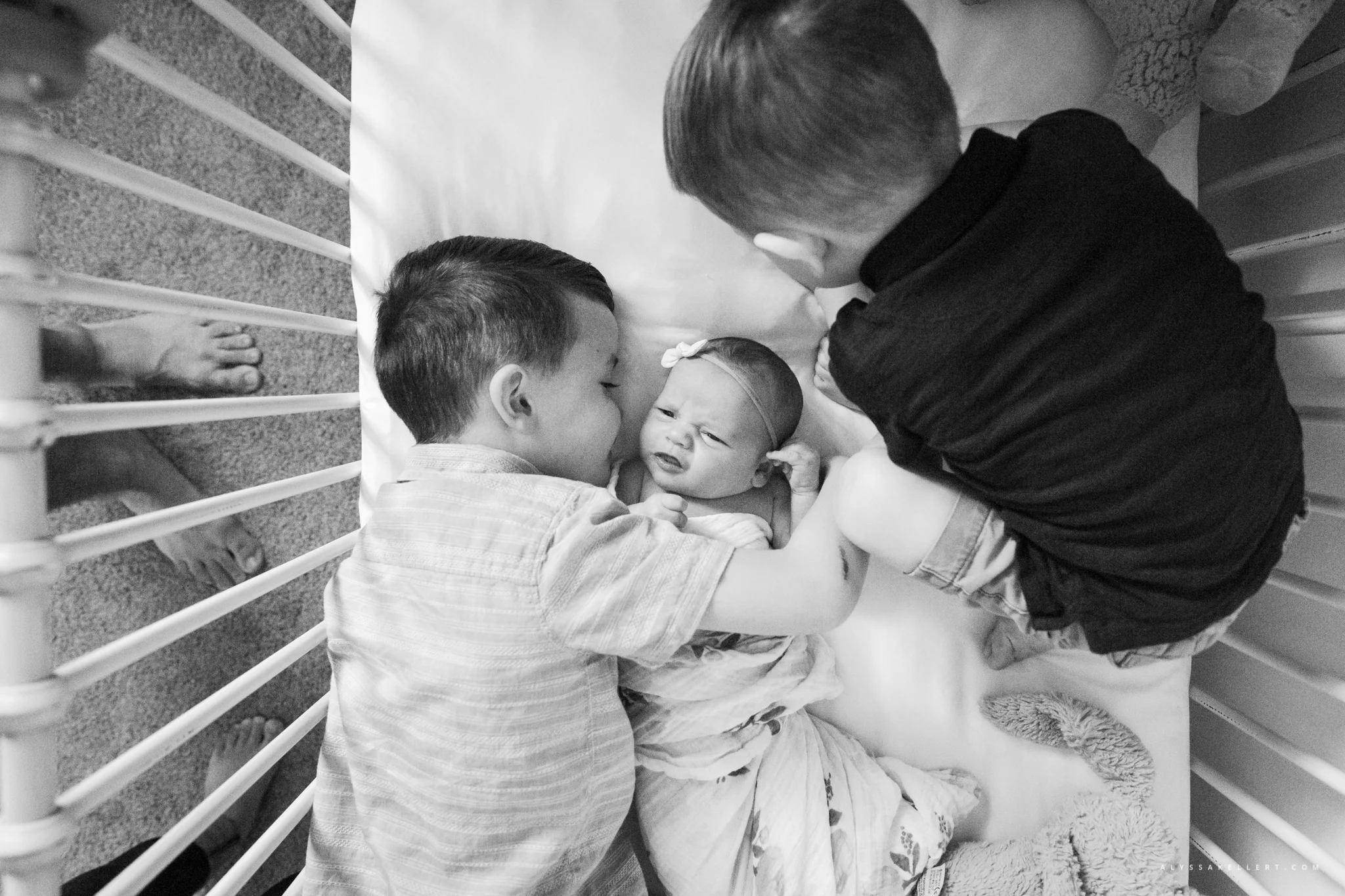 brothers cuddling baby sister in crib during documentary lifestyle session photography