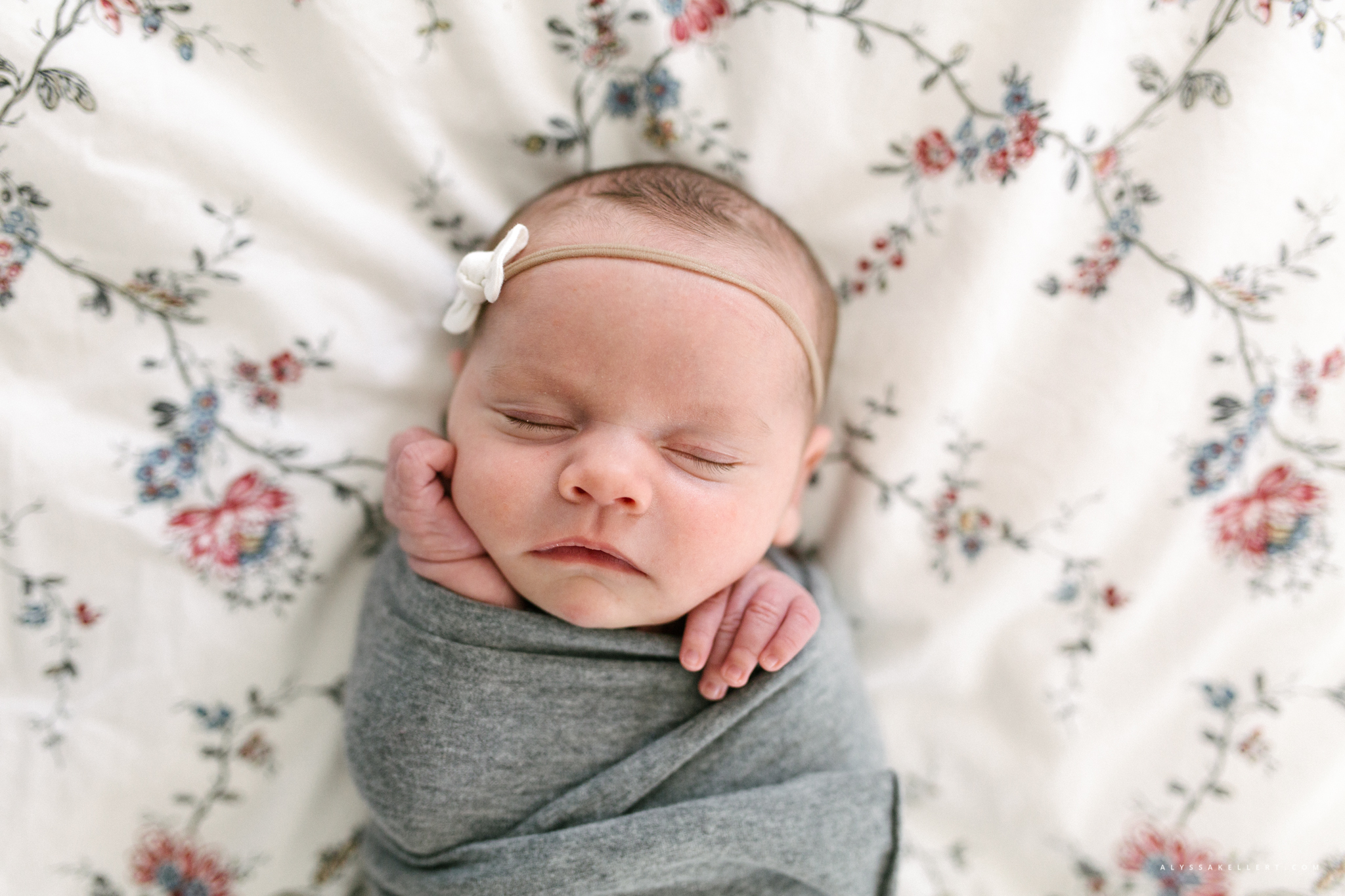 looking down on baby girl lying on parents bed during photography session