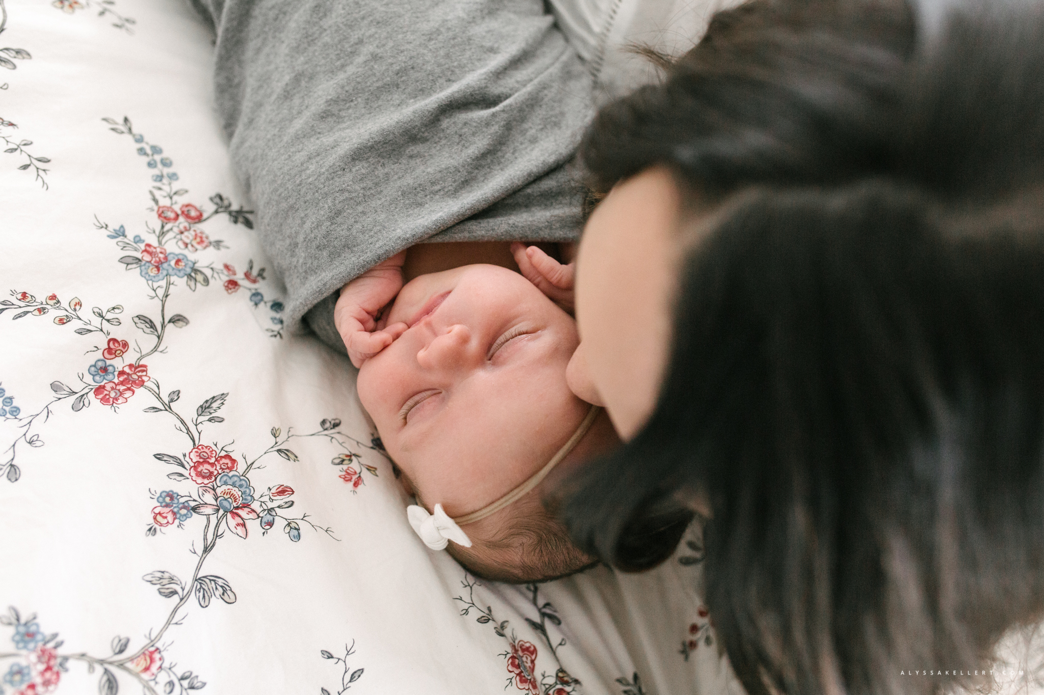 mom kissing baby girl on bed