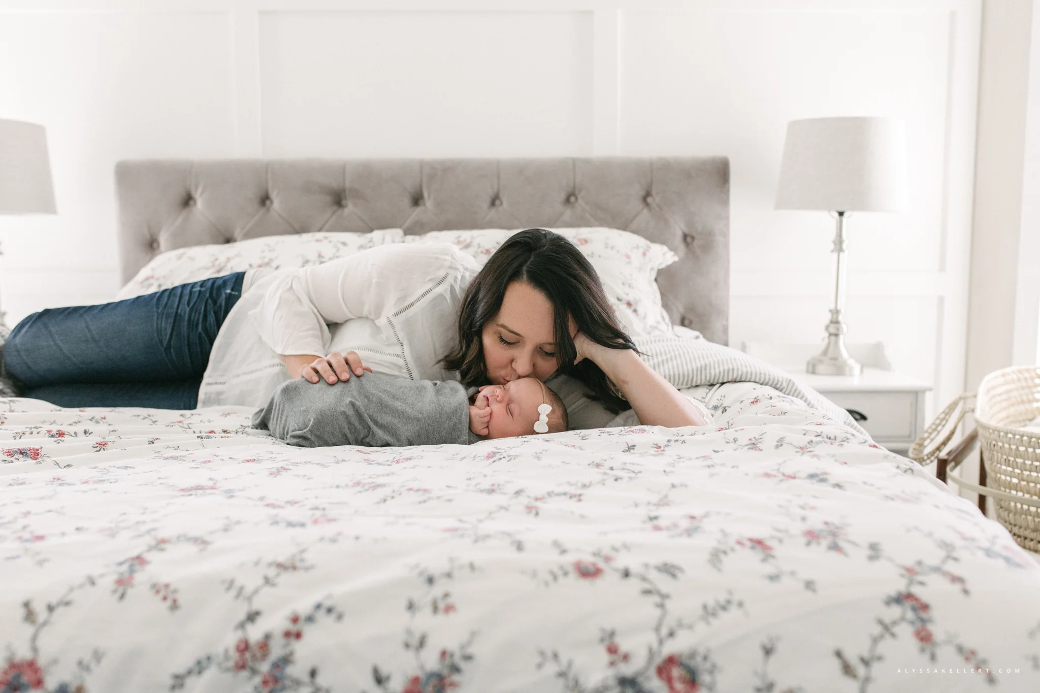 mom looking at her newborn lying on her bed in mission bc