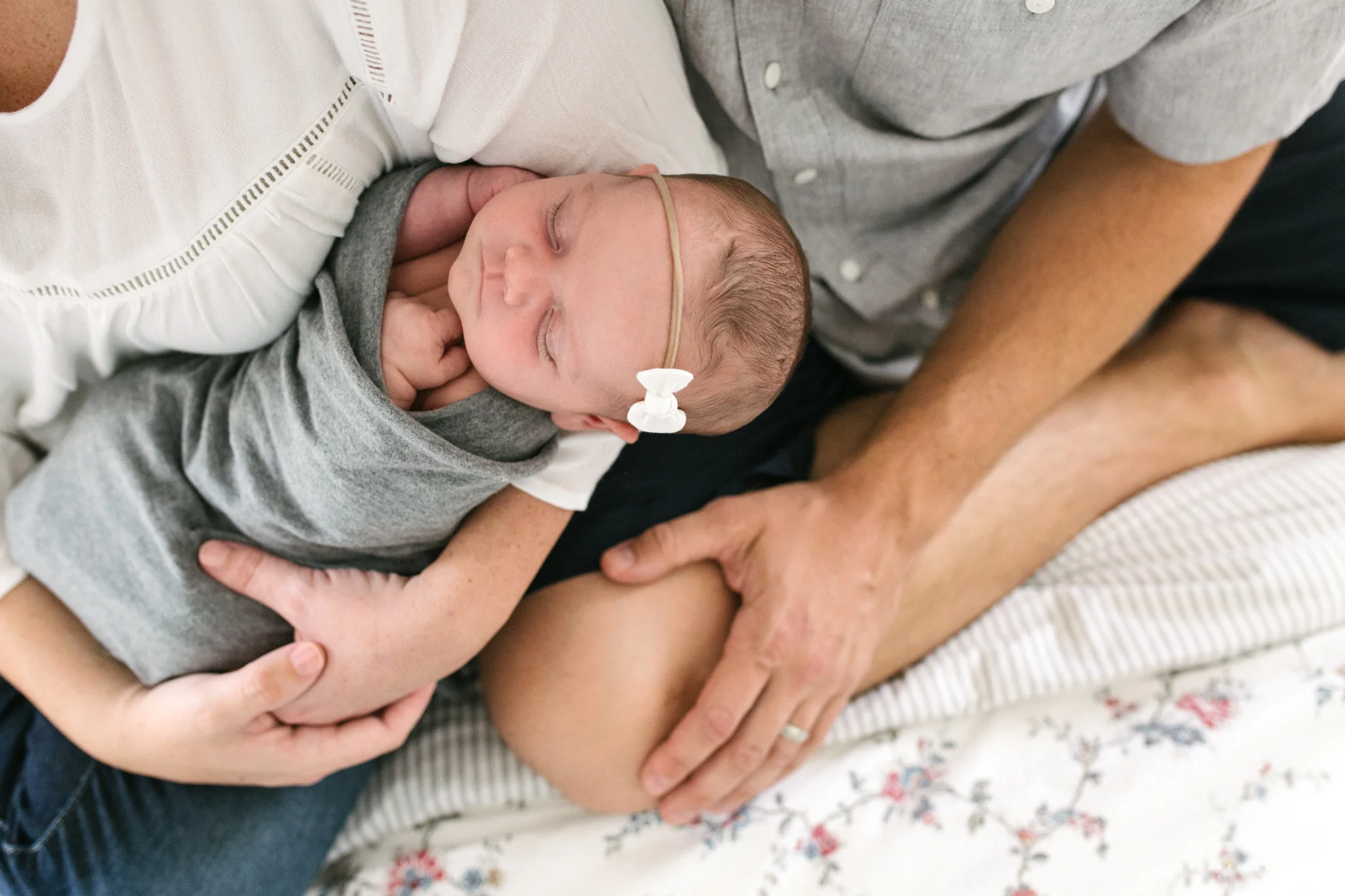 parents holding baby newborn girl on bed