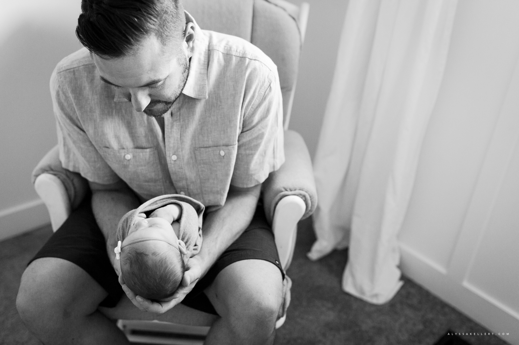 dad looking at his newborn baby girl in the nursery
