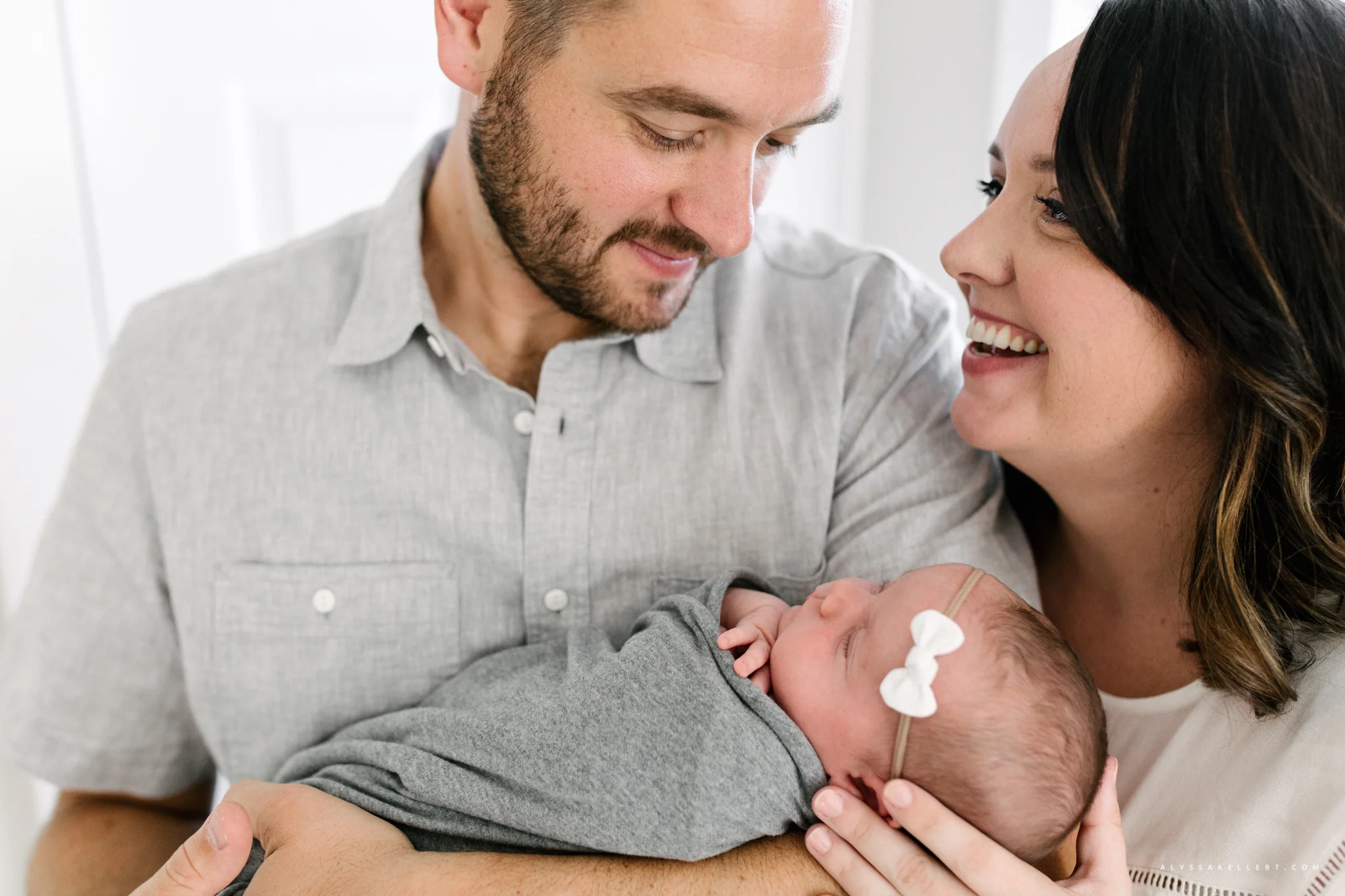 parents holding their baby girl by the window during lifestyle newborn photo shoot