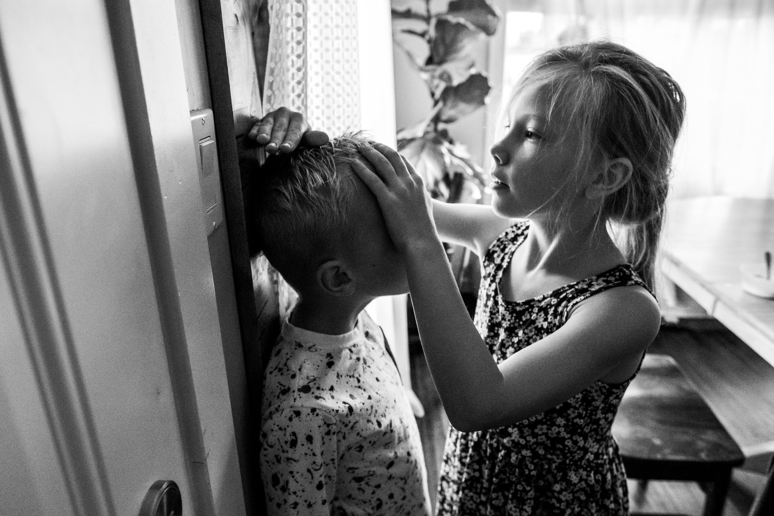 big sister measuring little brother's height at home wooden ruler