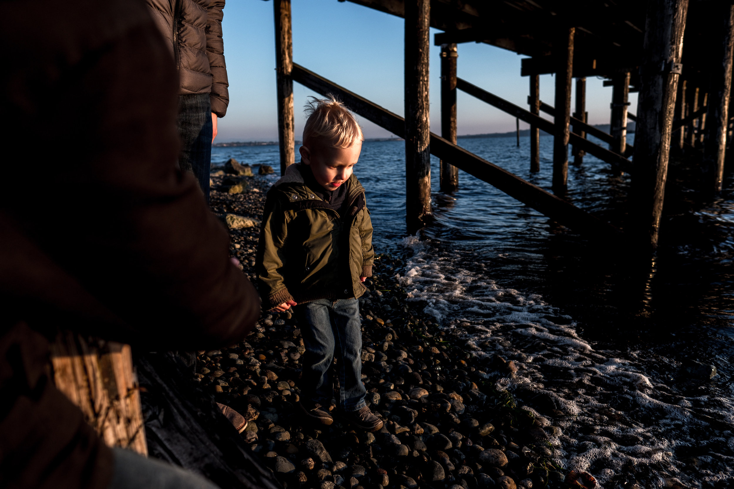 little boy toddler walking under dock at ocean