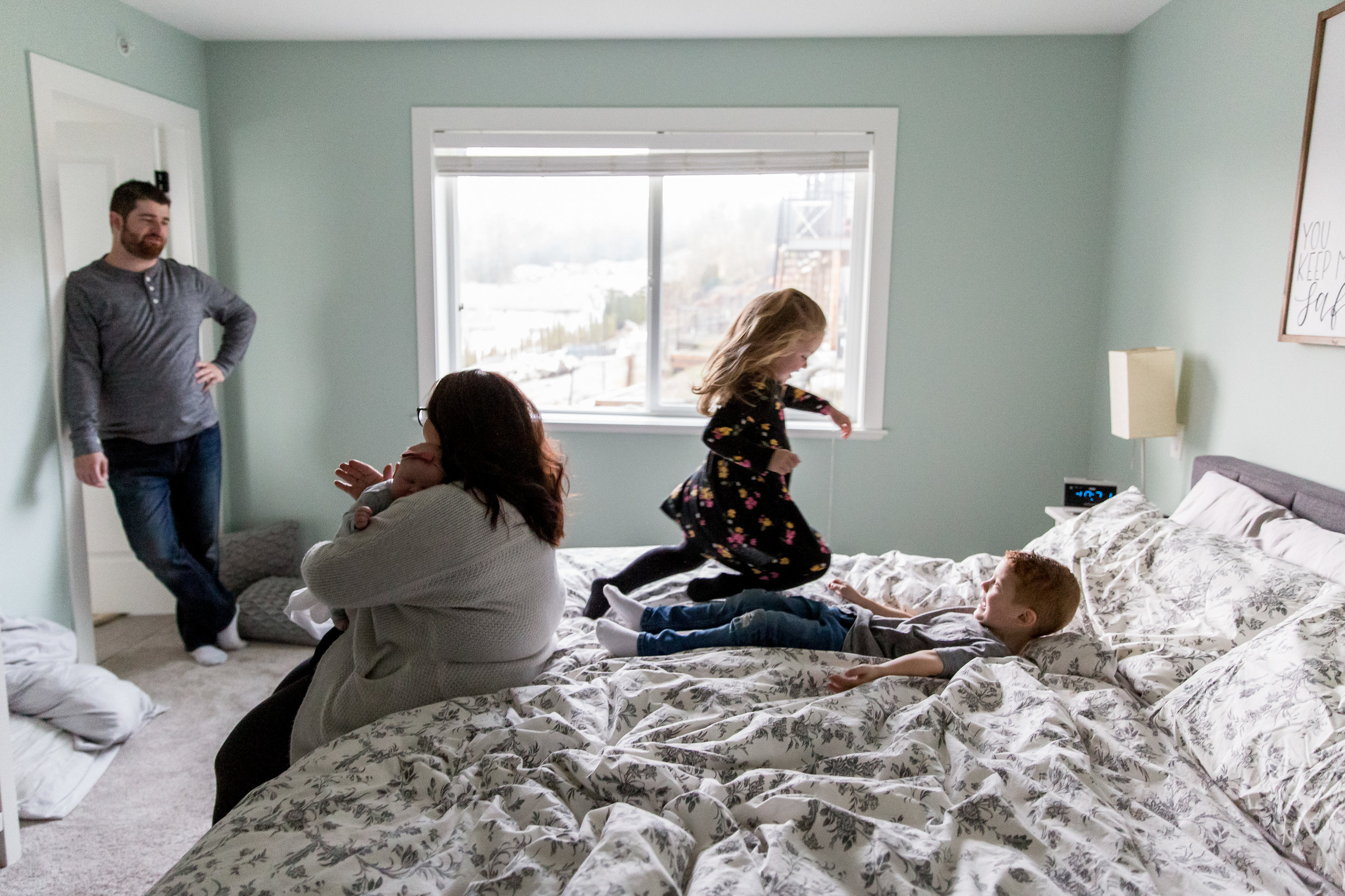 kids jumping on bed with mom and dad feeding newborn baby maple ridge